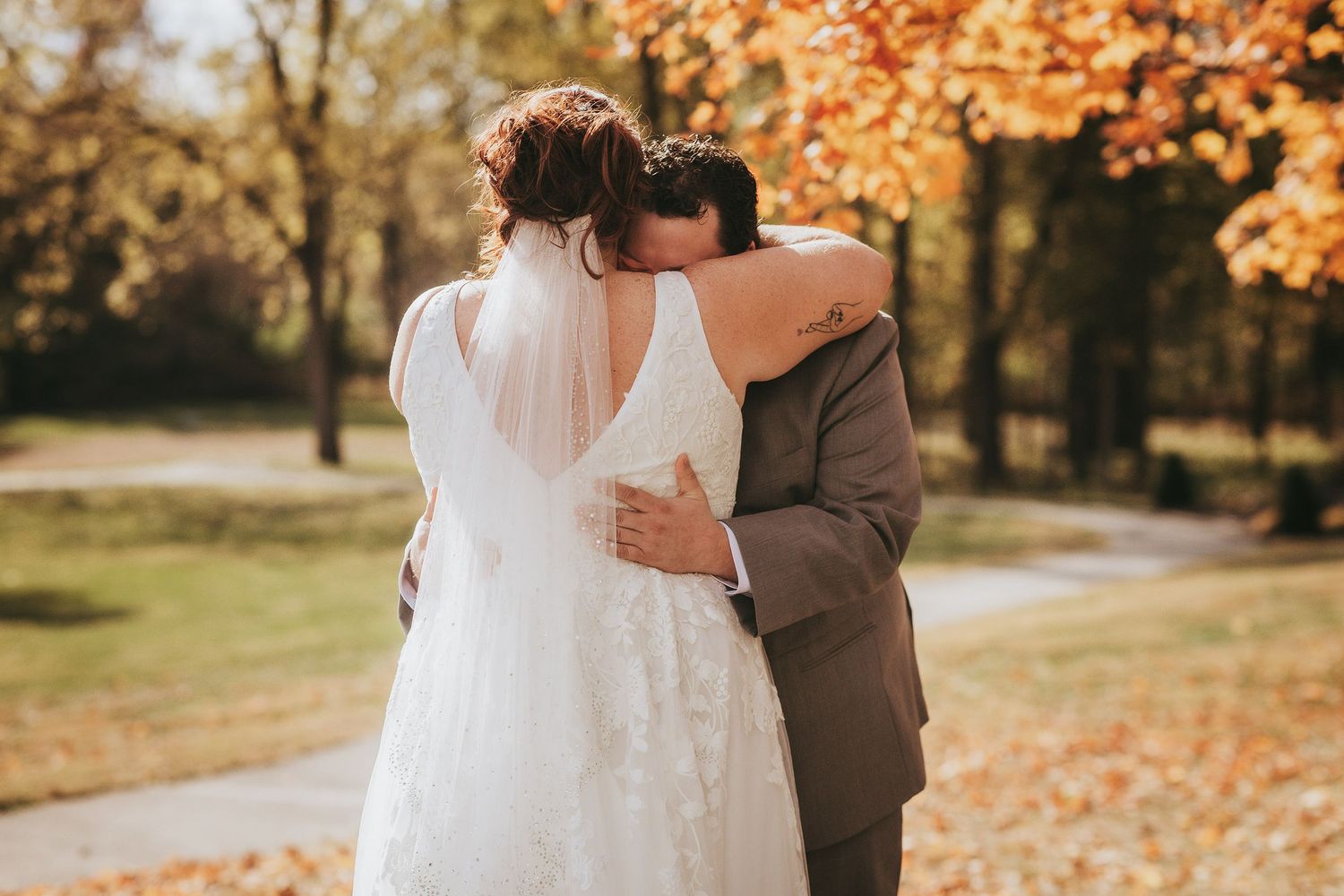 Romantic autumn wedding moment with golden leaves in background.