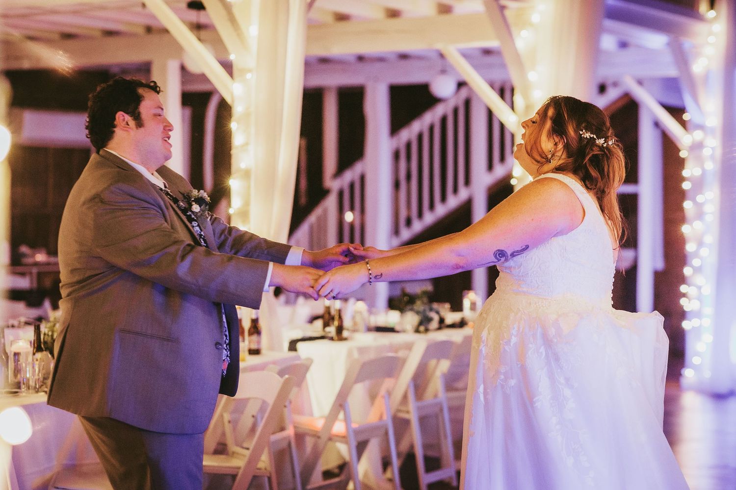 Romantic first dance moment captured under purple venue lighting and white decorative elements.