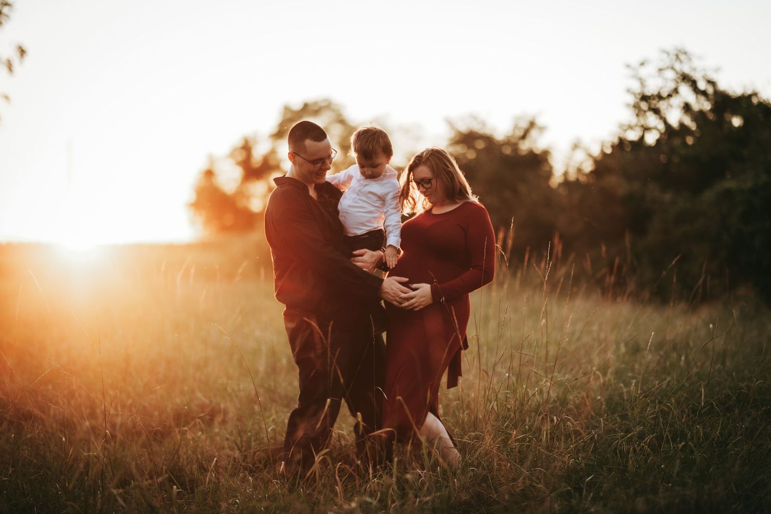 A couple dances together in a golden sunlit field during sunset creating a romantic silhouette.