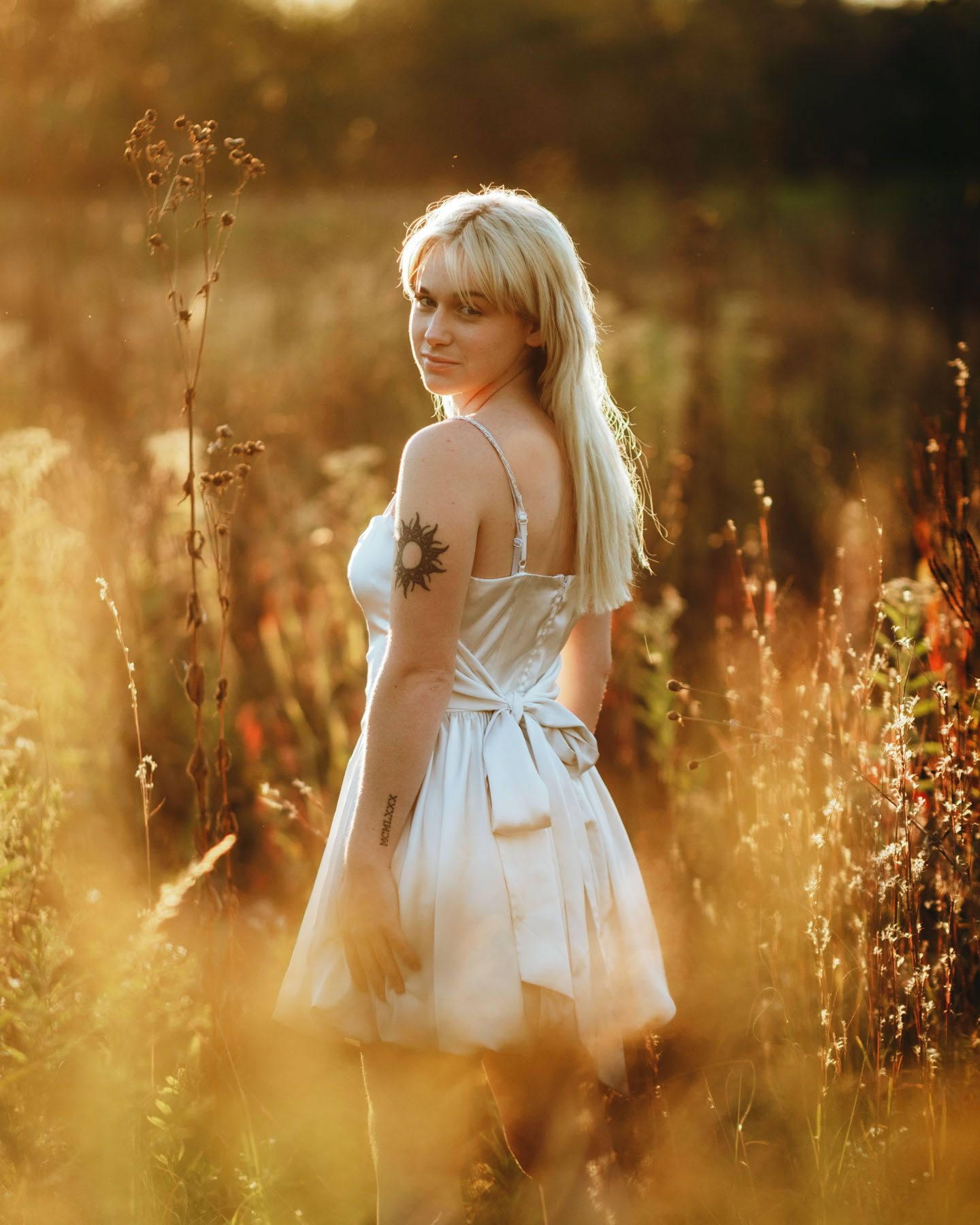 Artistic portrait series captured in a sunlit field with soft bokeh and warm golden hour lighting.