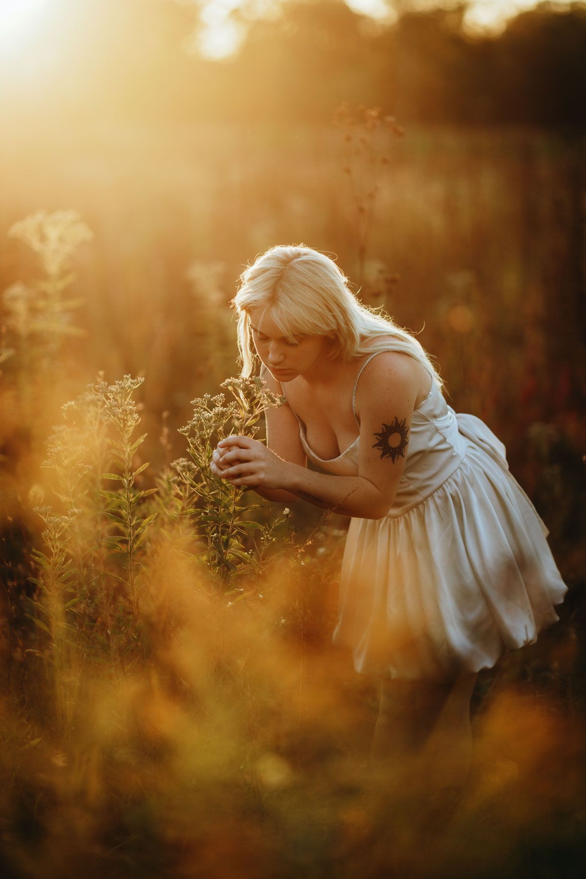 A series of dreamy golden-hour photos showing someone in a white dress bending down among wildflowers in a meadow.