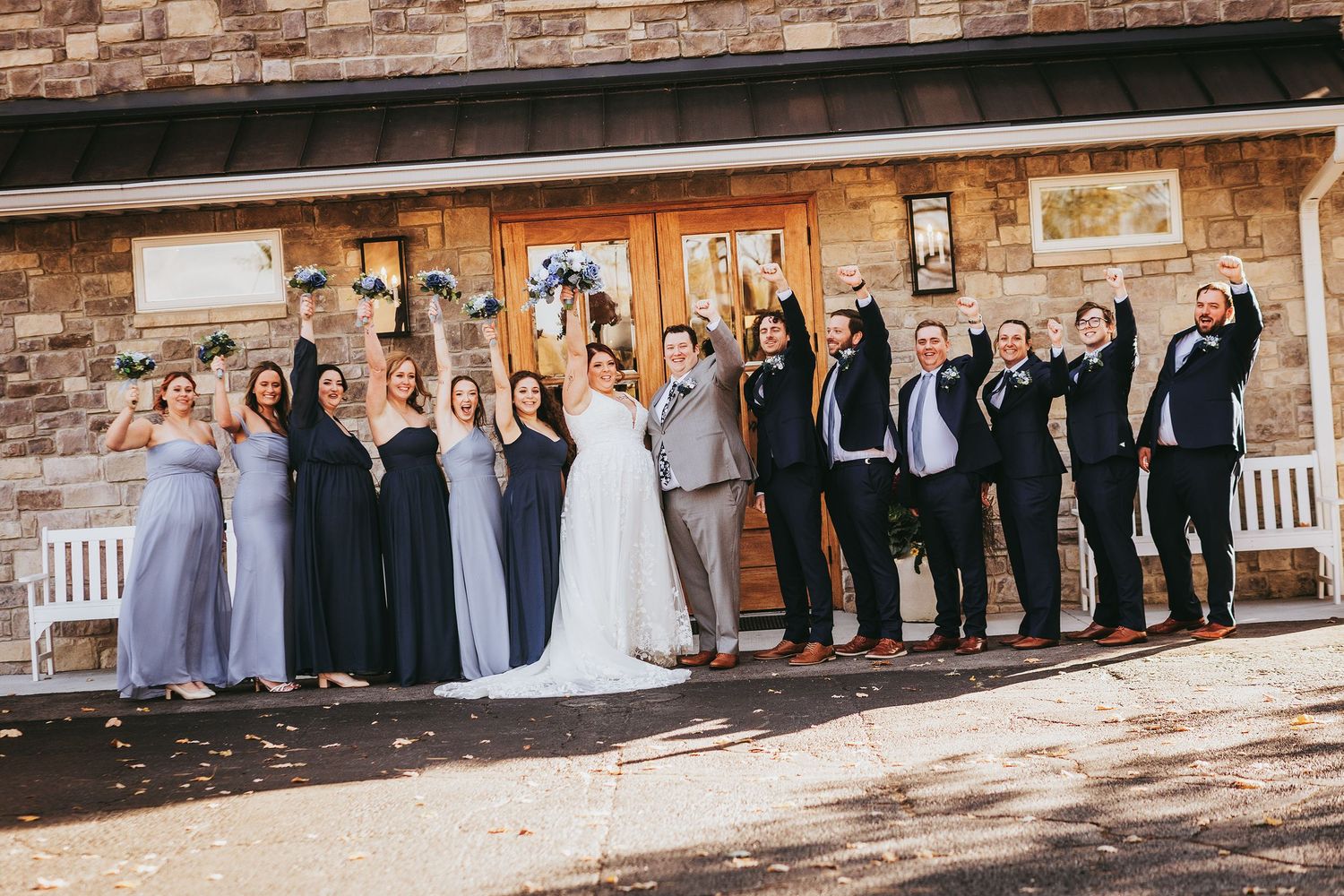Wedding party members lined up against a rustic stone wall background.