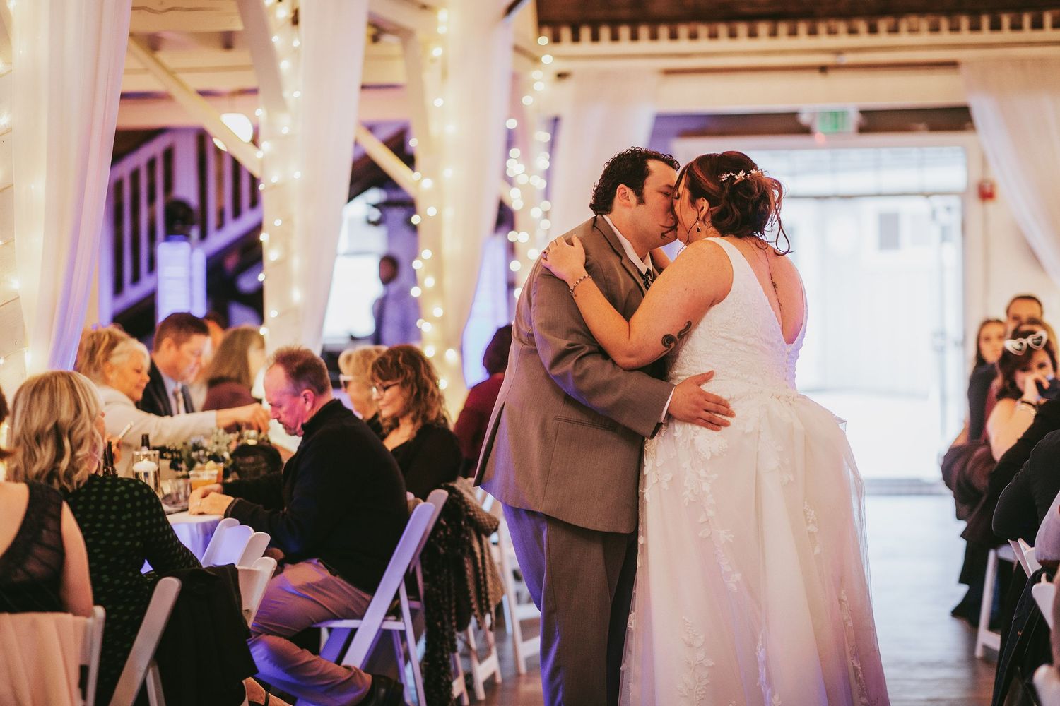 Couples dancing together at an indoor wedding reception with purple ambient lighting.