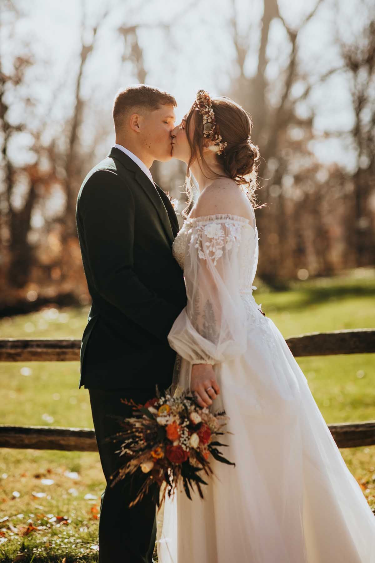 A romantic autumn wedding portrait with a couple embracing against a backdrop of fall foliage.