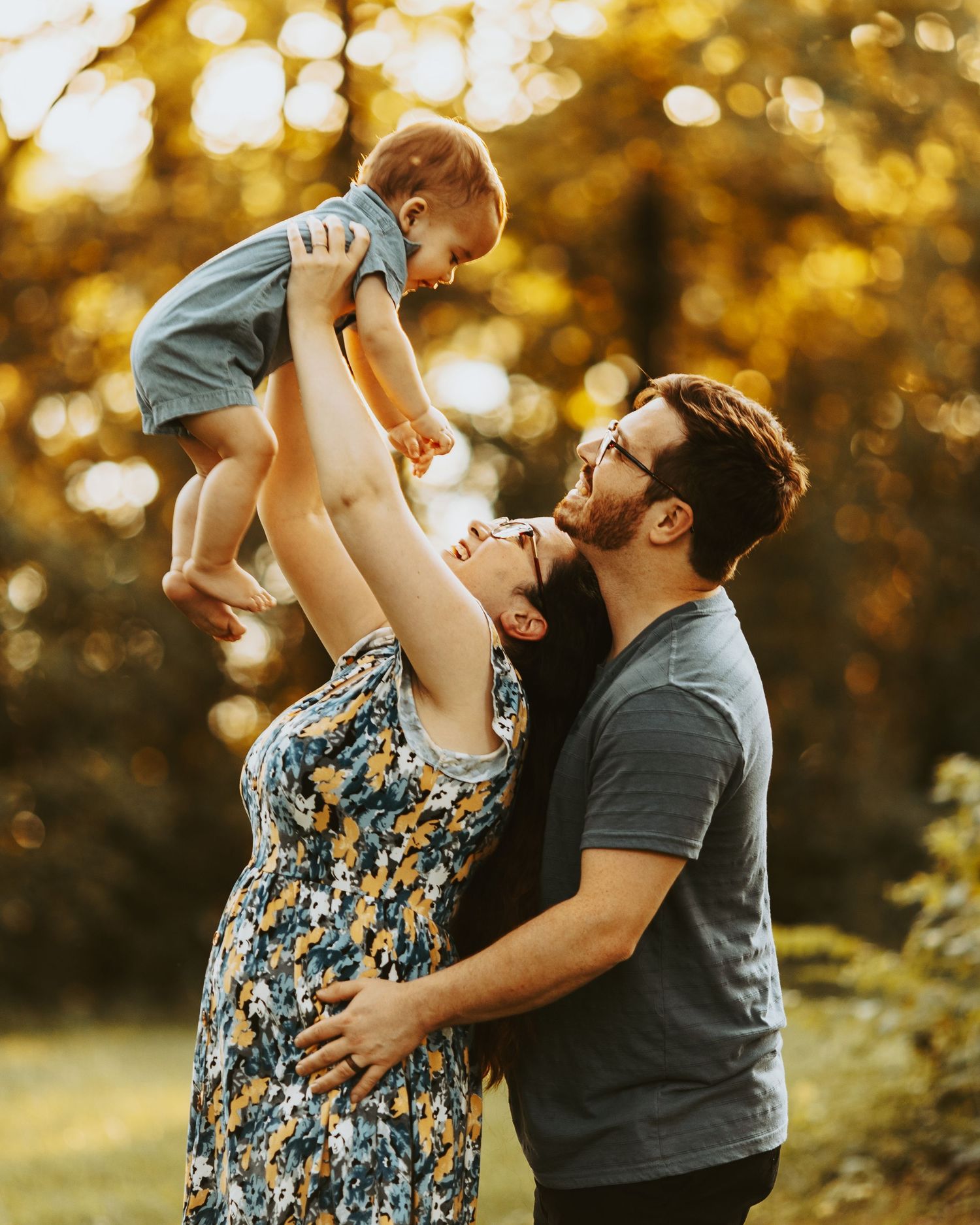 A family shares joyful moments together in a sunlit autumn setting with golden bokeh in the background.