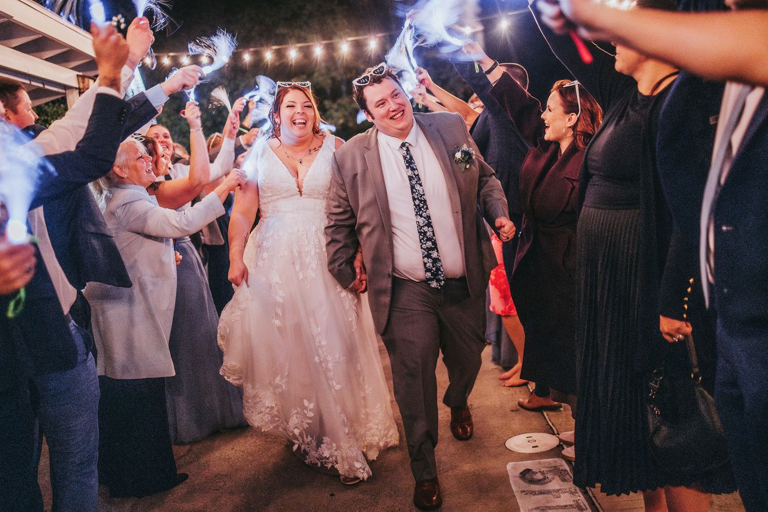 Festive outdoor wedding celebration with string lights and dancing guests at night.
