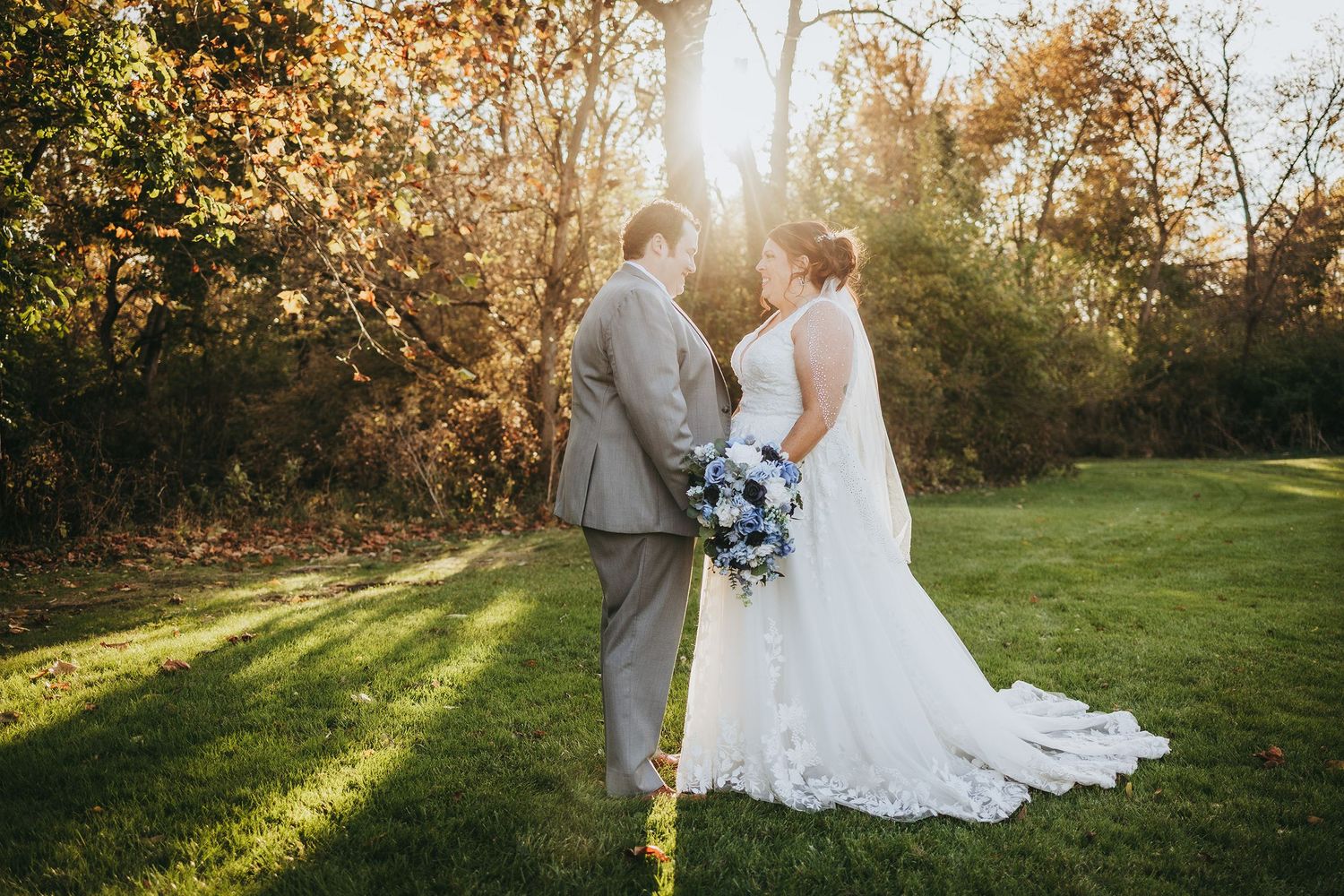 Wedding couple embracing in a sunlit meadow during golden hour.