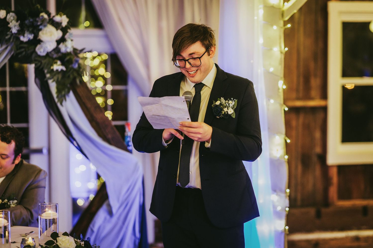 Wedding guest speaking into a microphone during a reception speech.