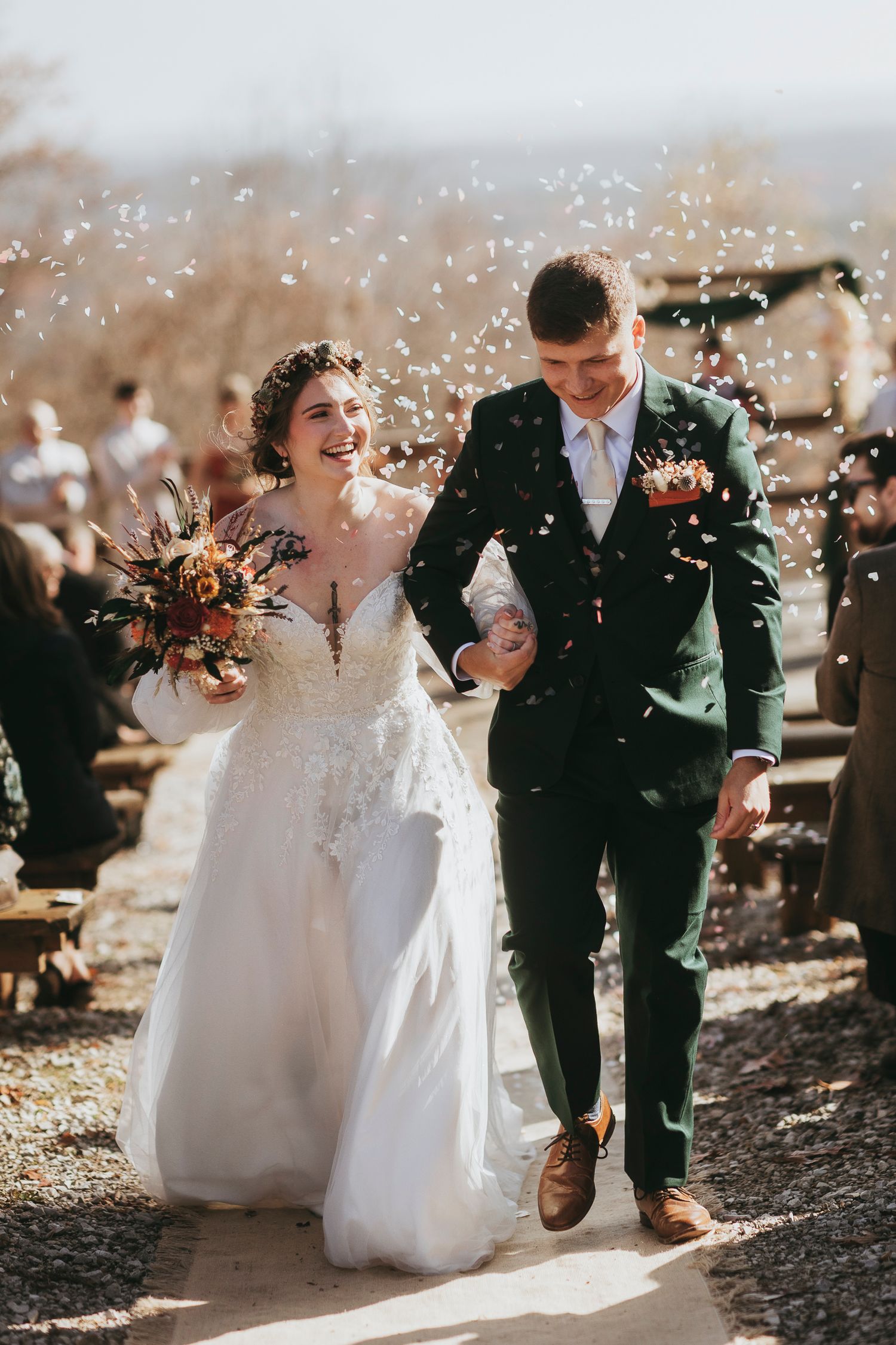 A joyful wedding couple shares a candid moment together while walking outdoors on a sunny autumn day.
