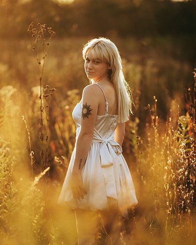 A dreamy golden hour portrait series in a wildflower meadow with soft sunlight filtering through tall grass.
