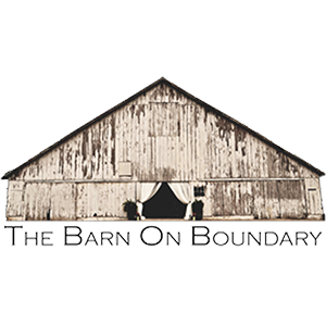 A rustic white weathered barn with triangular roof and text reading 'The Barn On Boundary' below.