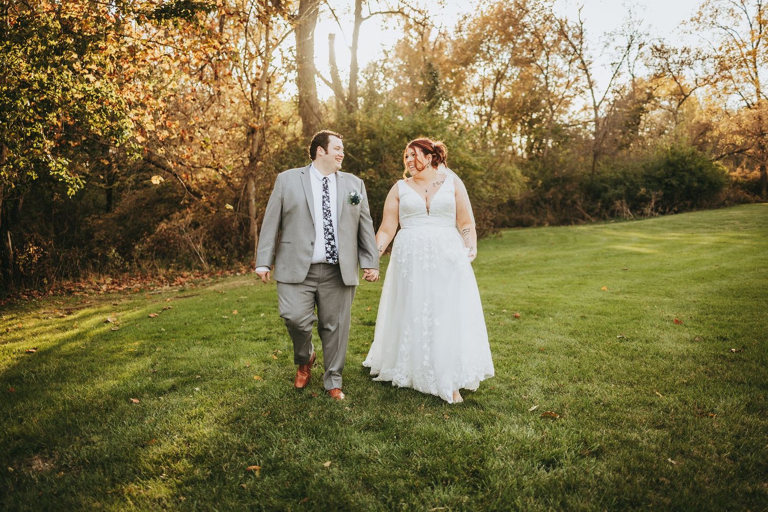 Autumn wedding photos captured in a scenic wooded area with golden sunlight.