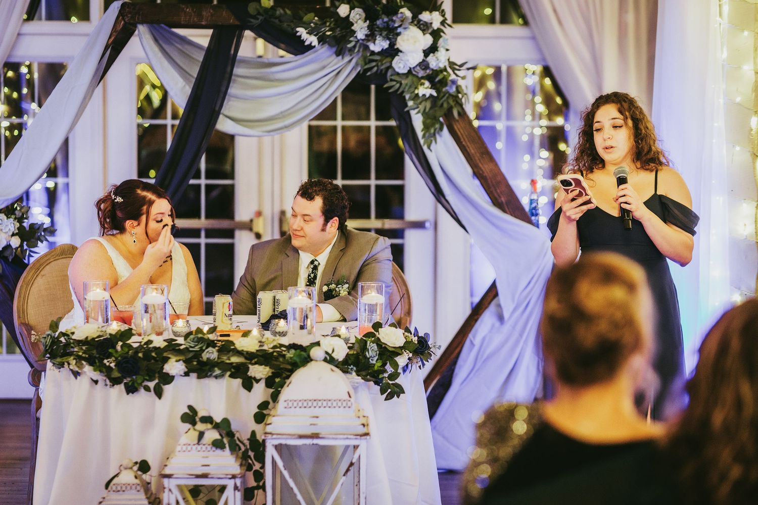 Elegant wedding reception venue decorated with white drapes and floral arrangements.