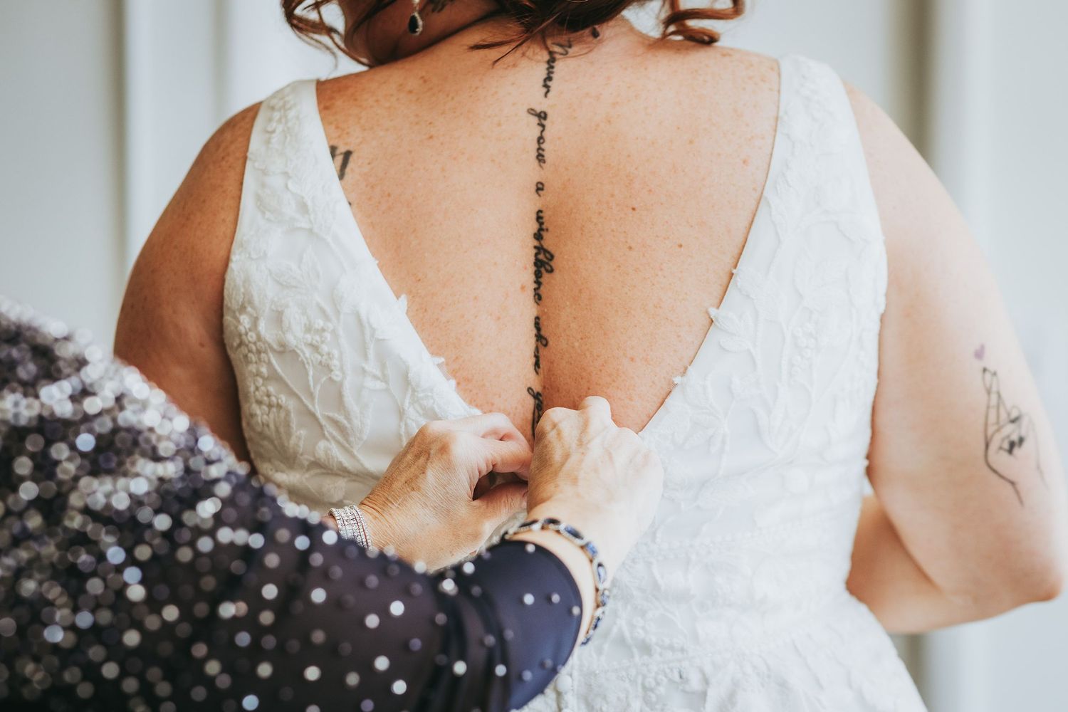 Wedding dress preparation scene showing intricate back details and buttons.
