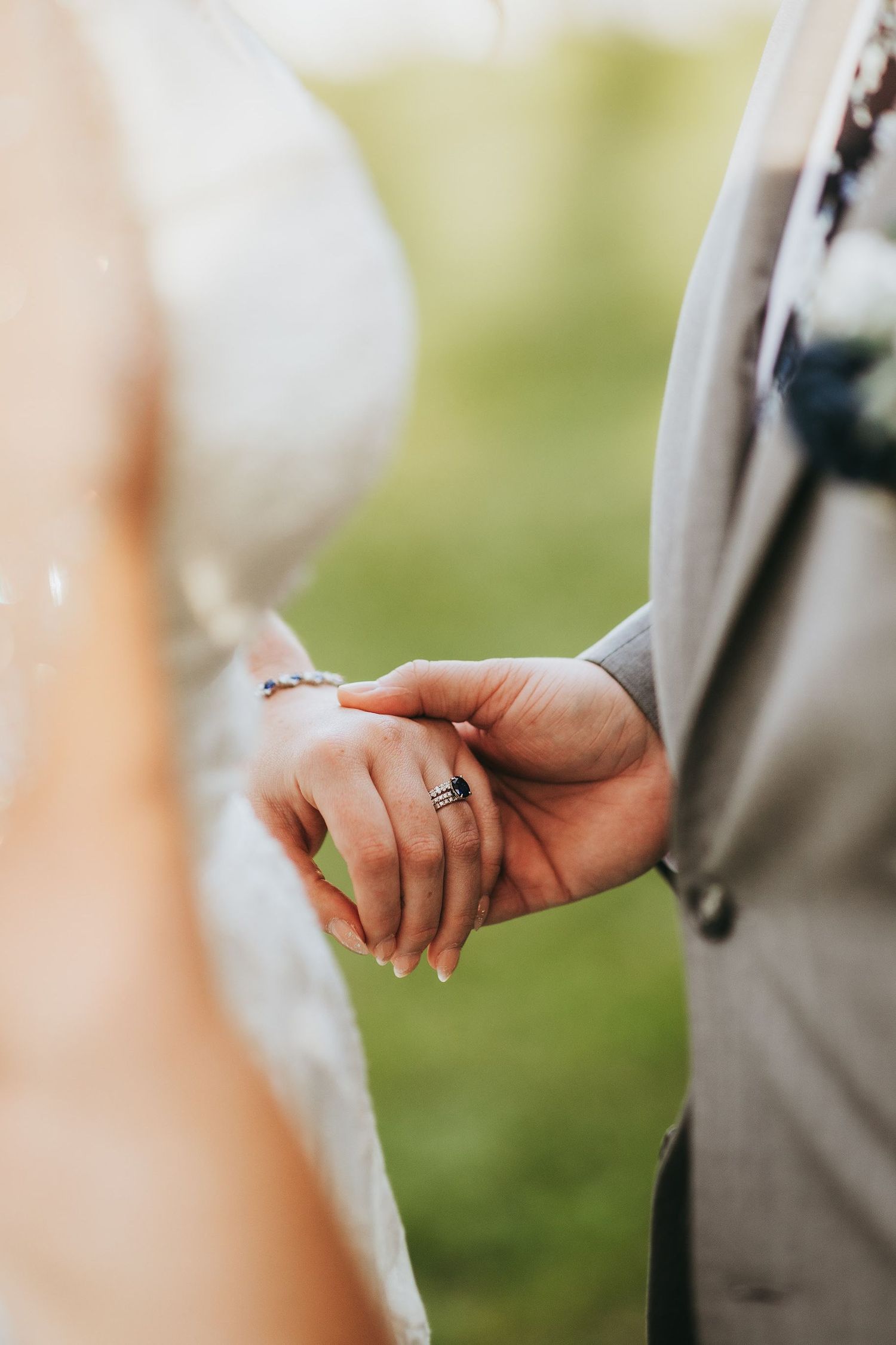 Close-up of hands holding rings during an intimate wedding ceremony moment.