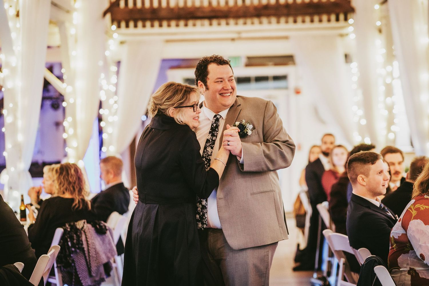 Wedding guests mingling and dancing at an elegantly lit indoor reception.