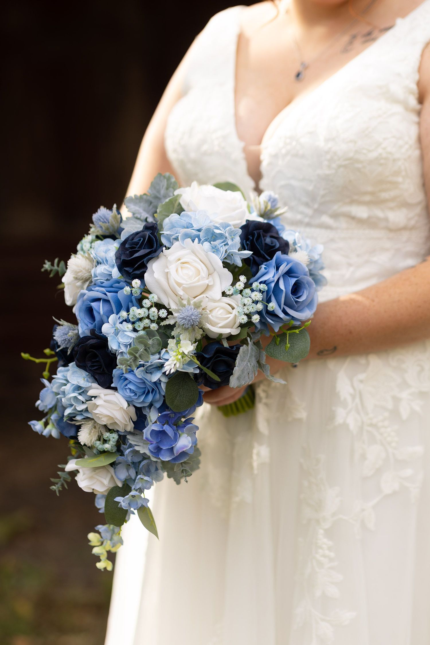 Blue and white floral bouquet details against white wedding dress.