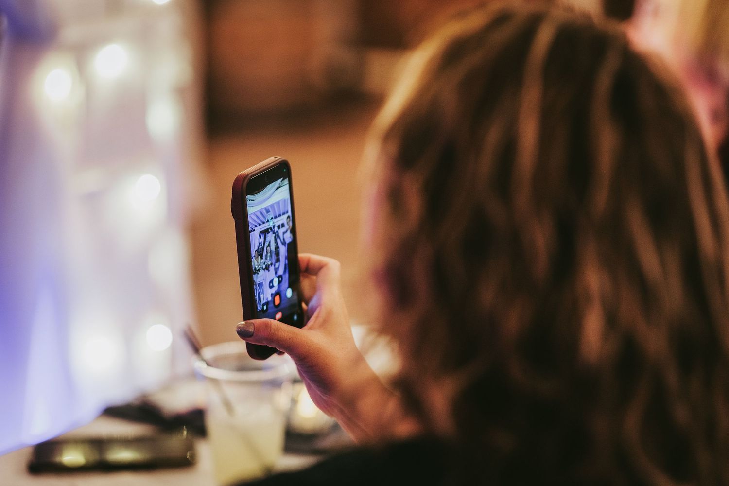 A guest captures a moment on their smartphone during a wedding reception.