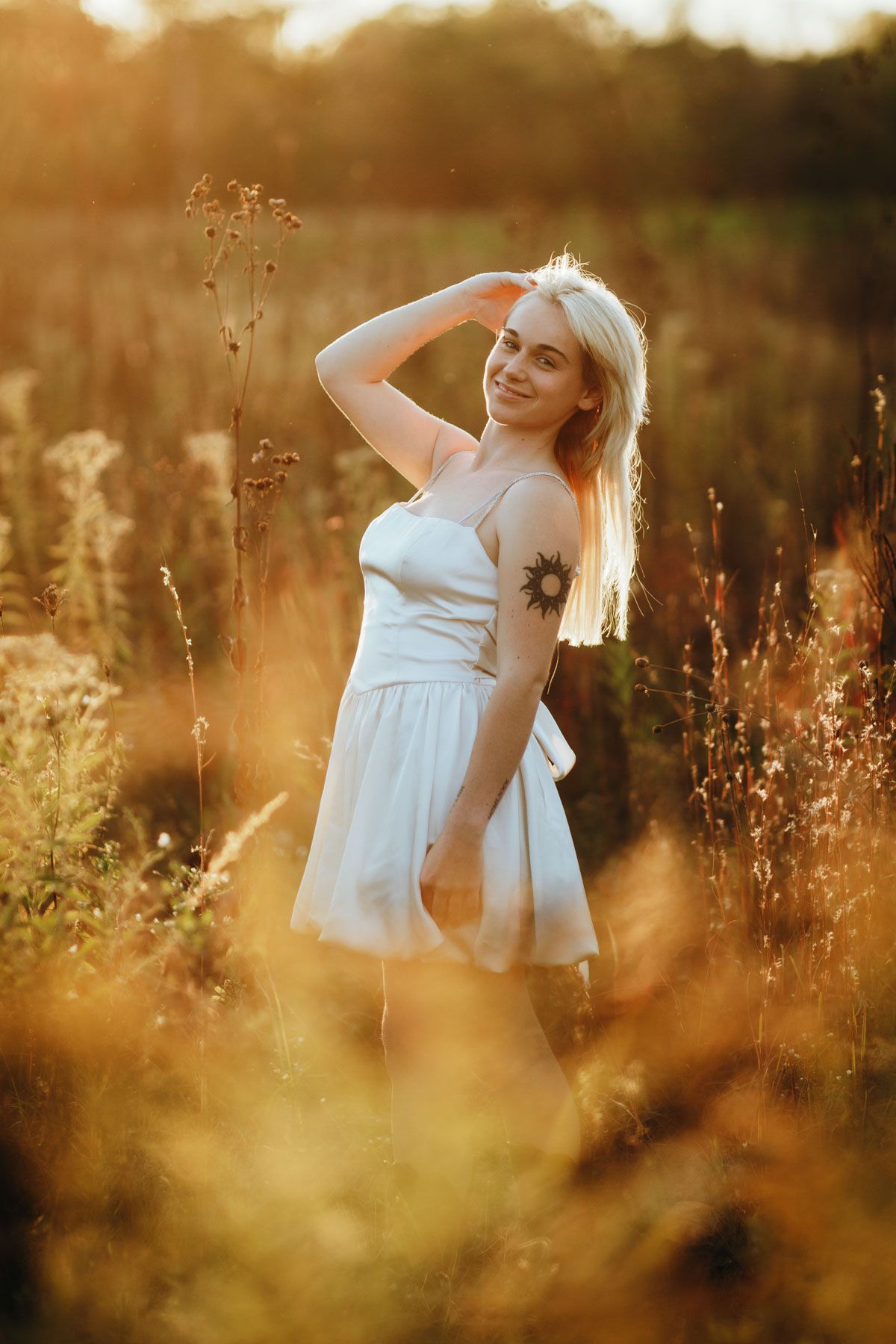 A dreamy sunset photoshoot in a golden meadow with tall grass and wildflowers as a white dress catches the warm light.