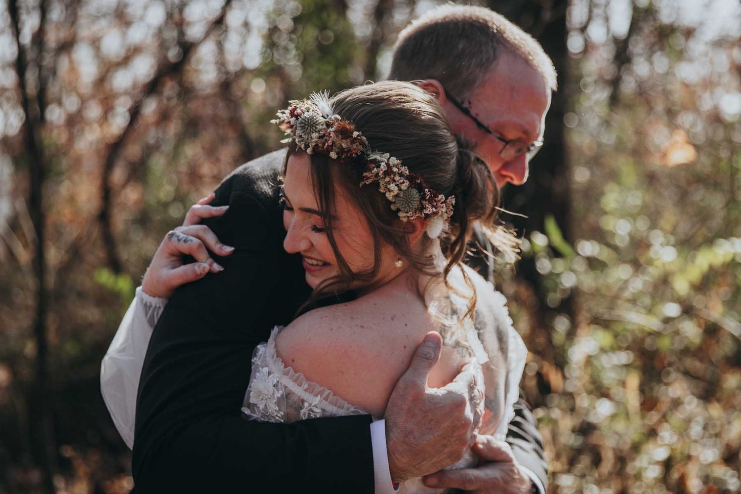 A couple in formal wedding attire share a romantic kiss outdoors during their autumn wedding ceremony.