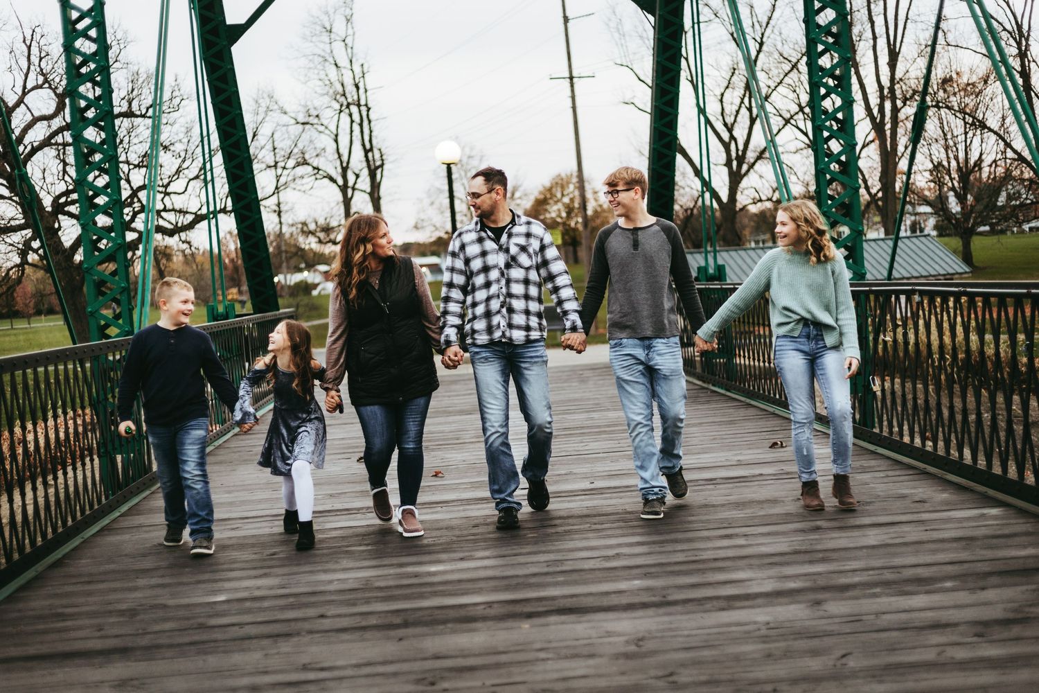 A group of people walking in sync on a wooden bridge with their legs visible from the knees down.