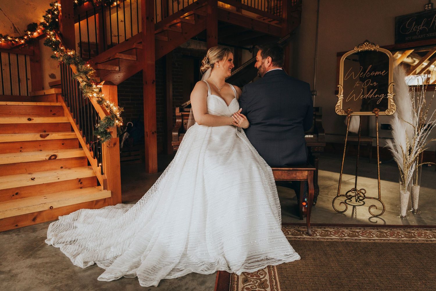 A couple in wedding attire dances together in a dimly lit rustic venue with wooden details and romantic lighting.