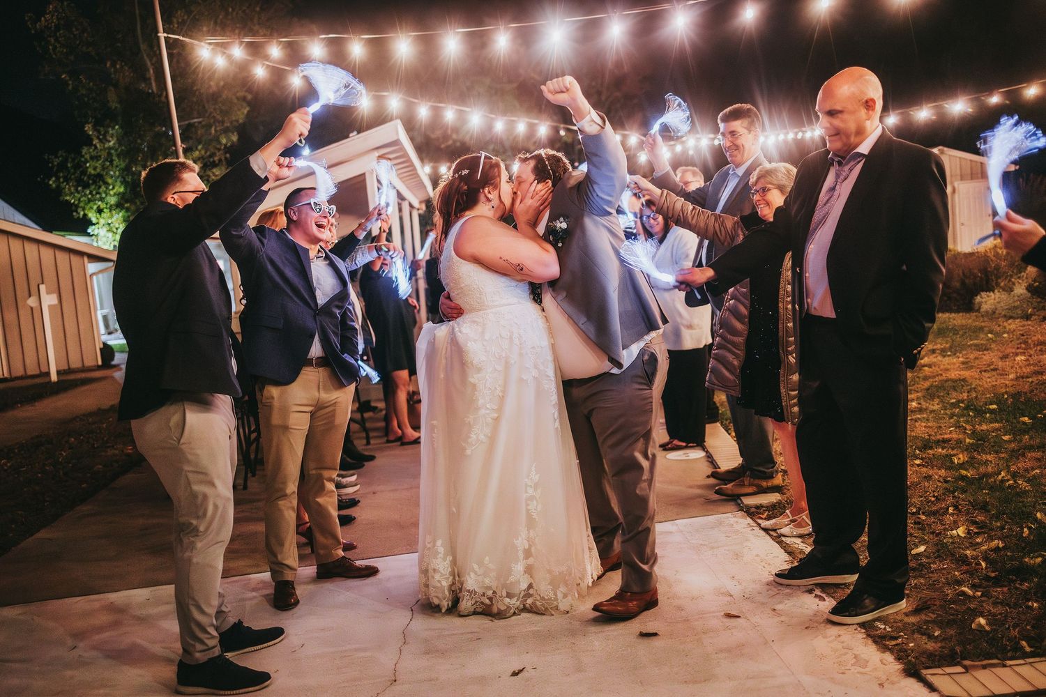 Wedding reception dance floor with string lights illuminating guests dancing in the evening.