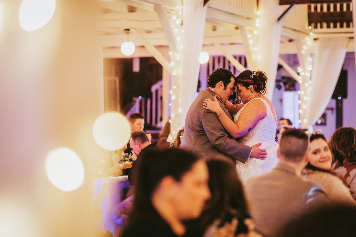 Wedding reception dance floor scene with soft lighting and decorative white draping.