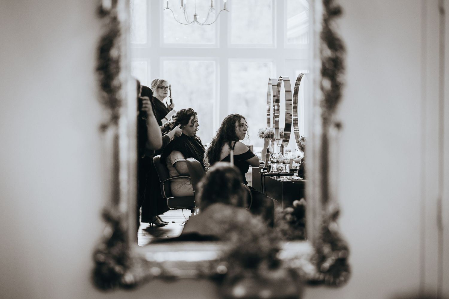 Artistic black and white shot through ornate mirror frame in bridal suite.