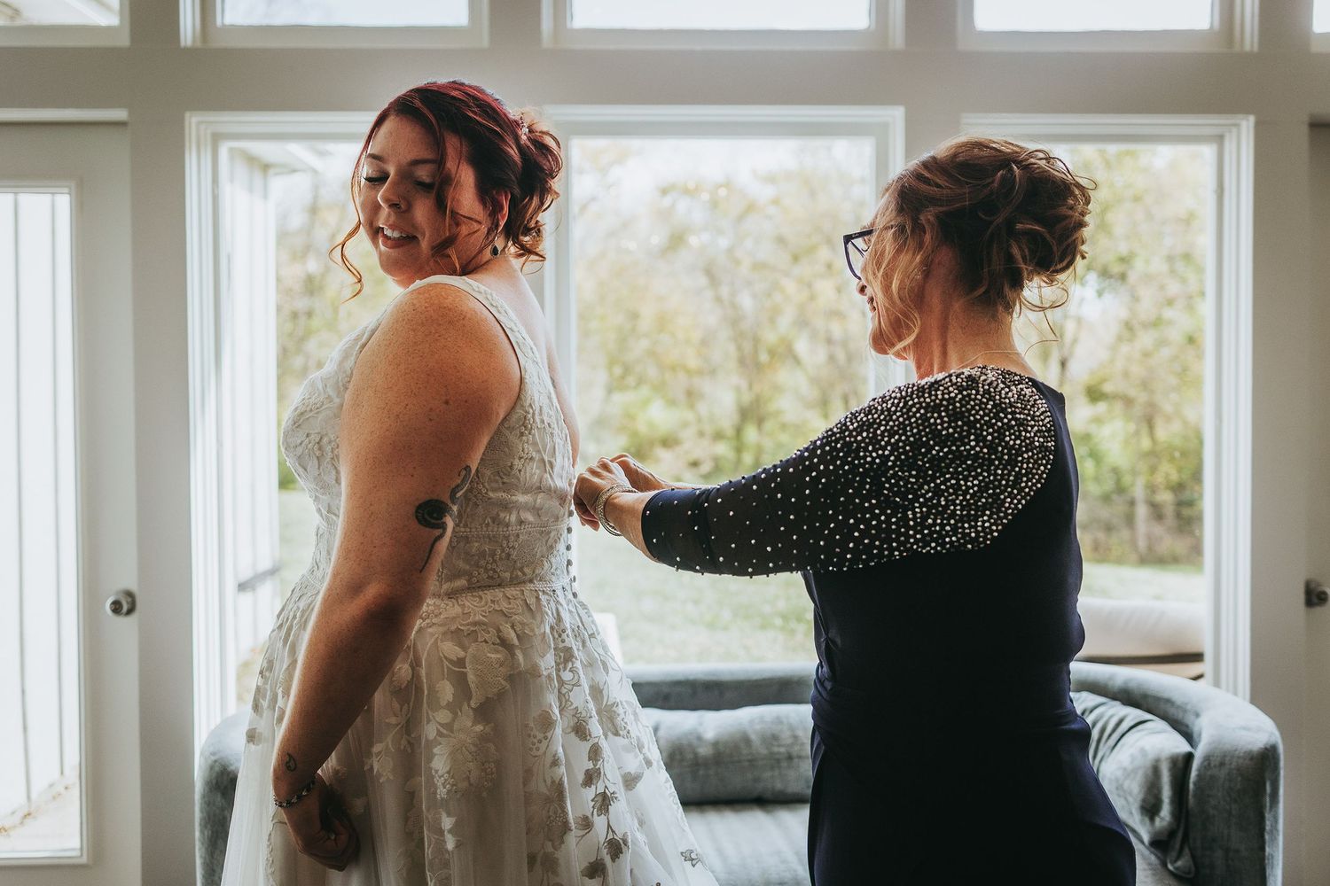 Wedding preparations by sunlit window with elegant white dress visible.