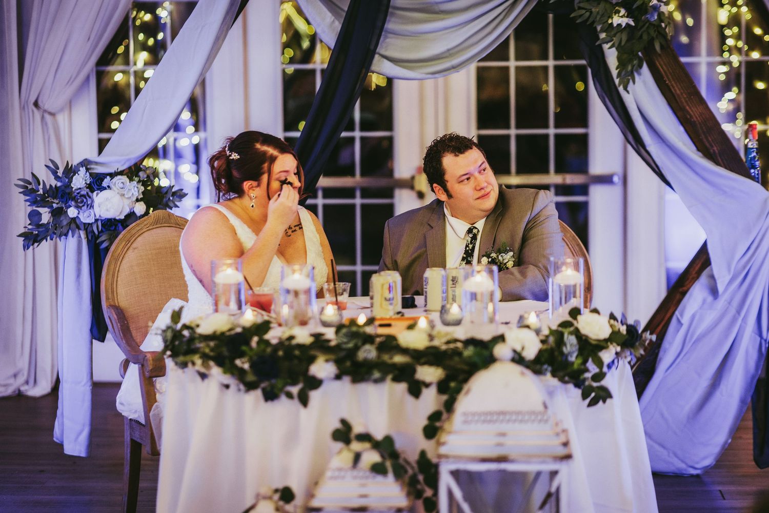 Wedding reception space with elegant draping and floral decorations along the ceiling.