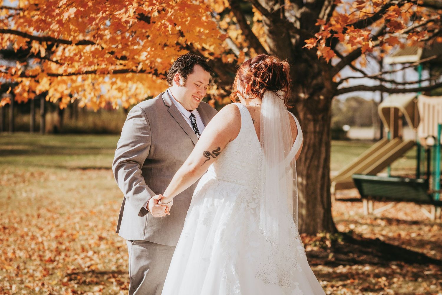 Autumn wedding scene with orange fall foliage in background.