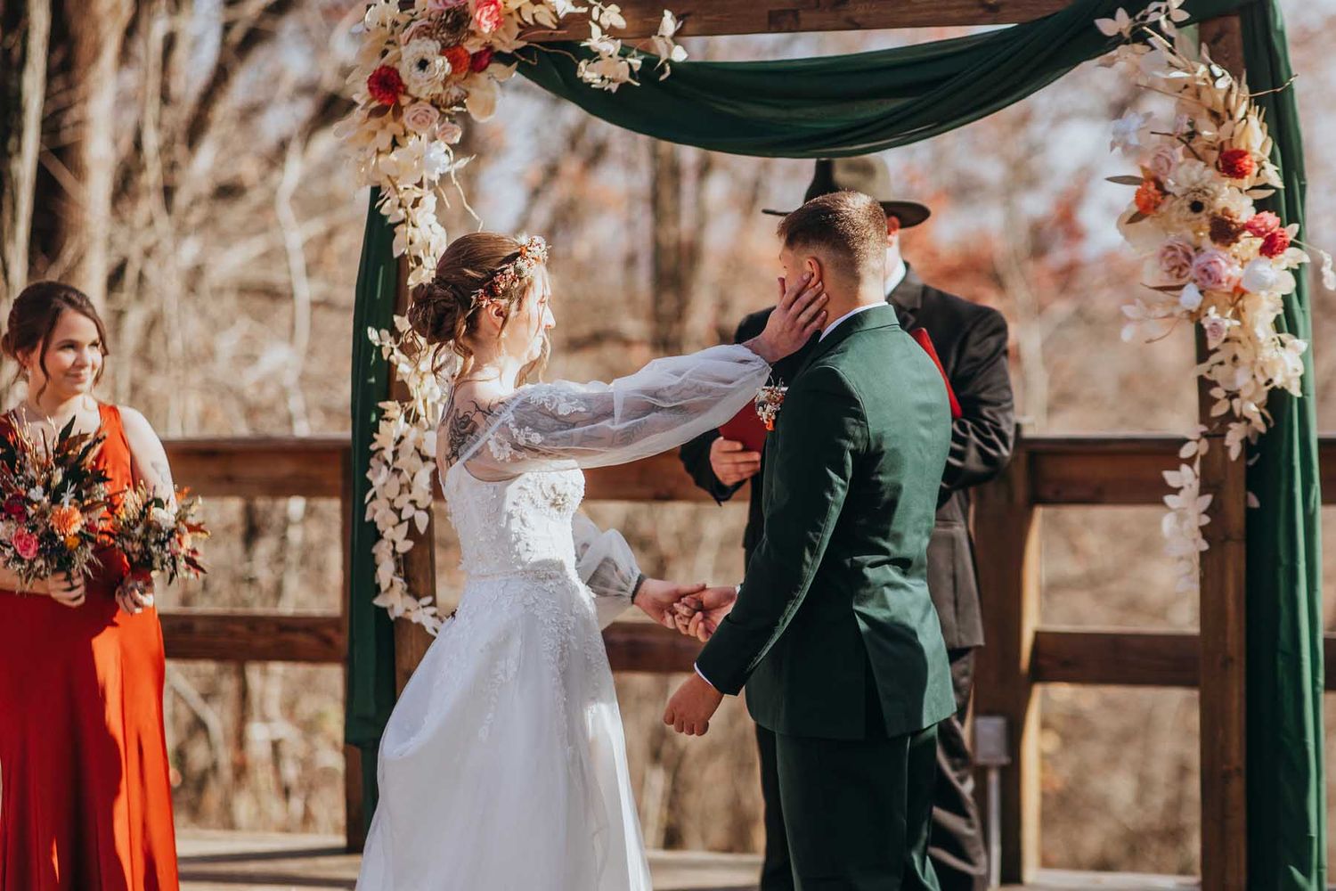 Wedding couple sharing a joyful moment during their outdoor ceremony with stone wall backdrop and floral decorations.
