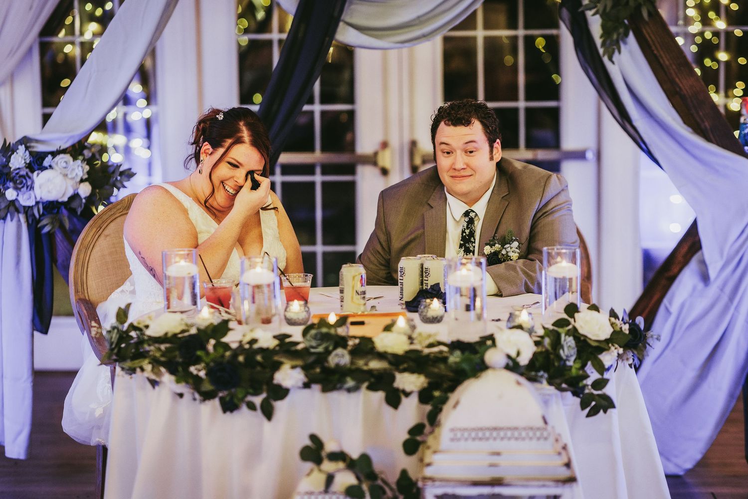 A couple shares an emotional moment at their wedding reception head table.