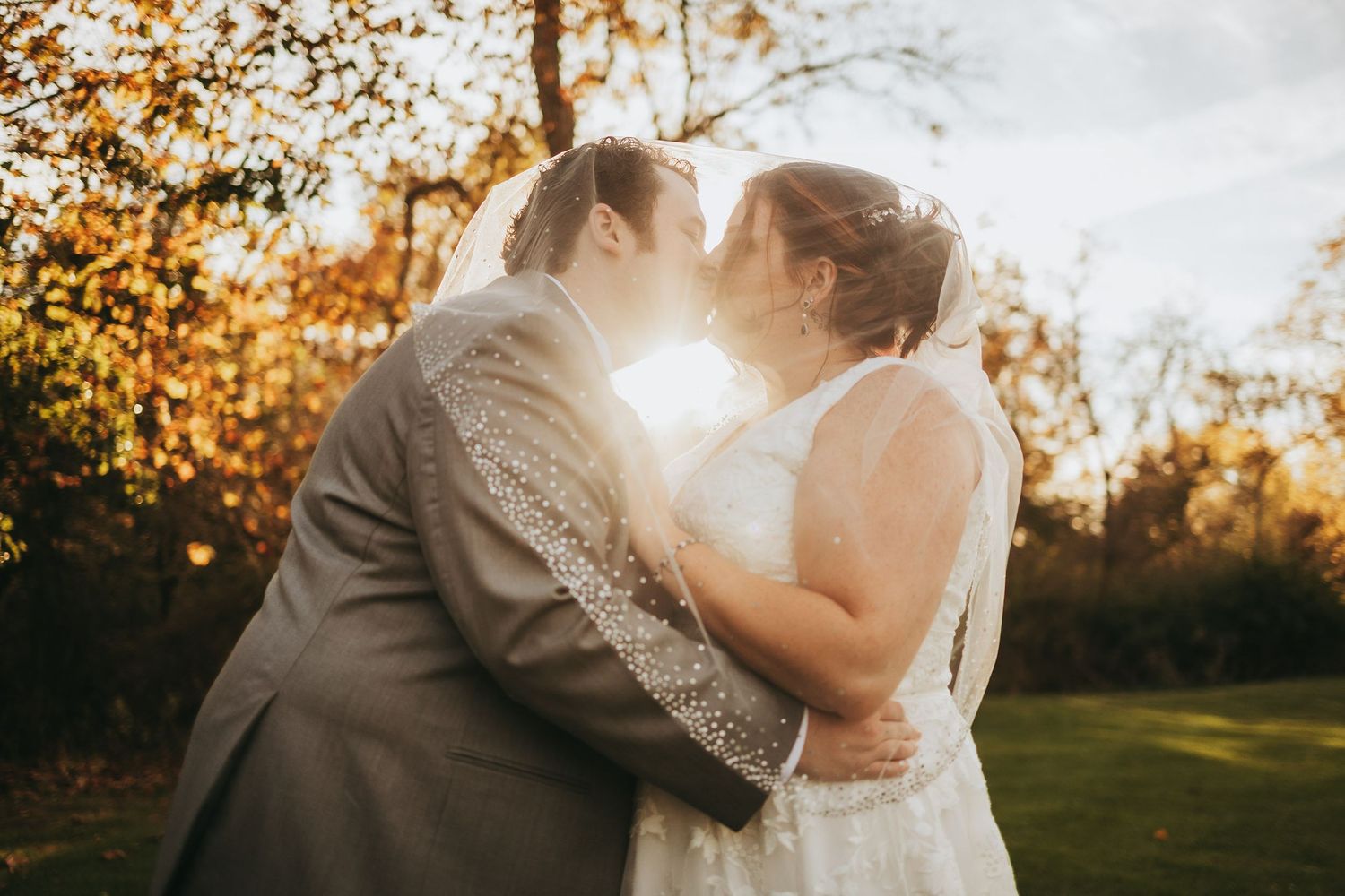Romantic sunset wedding portraits in a field with golden autumn light.