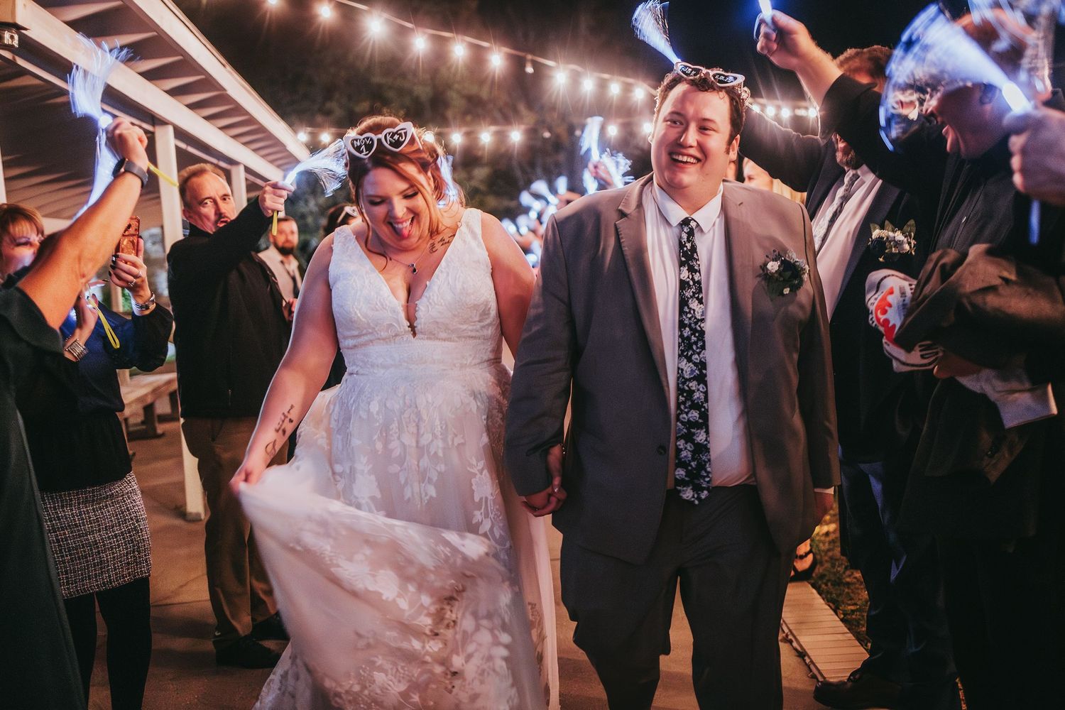 Wedding reception dance floor under string lights with guests celebrating.