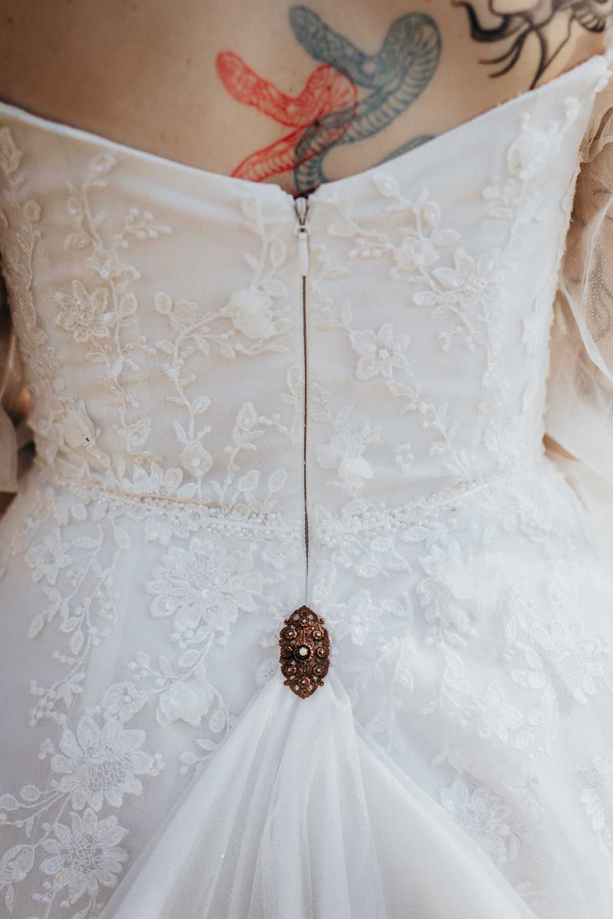 Close-up detail of an ornate wedding dress clasp with delicate lace and embroidered patterns.