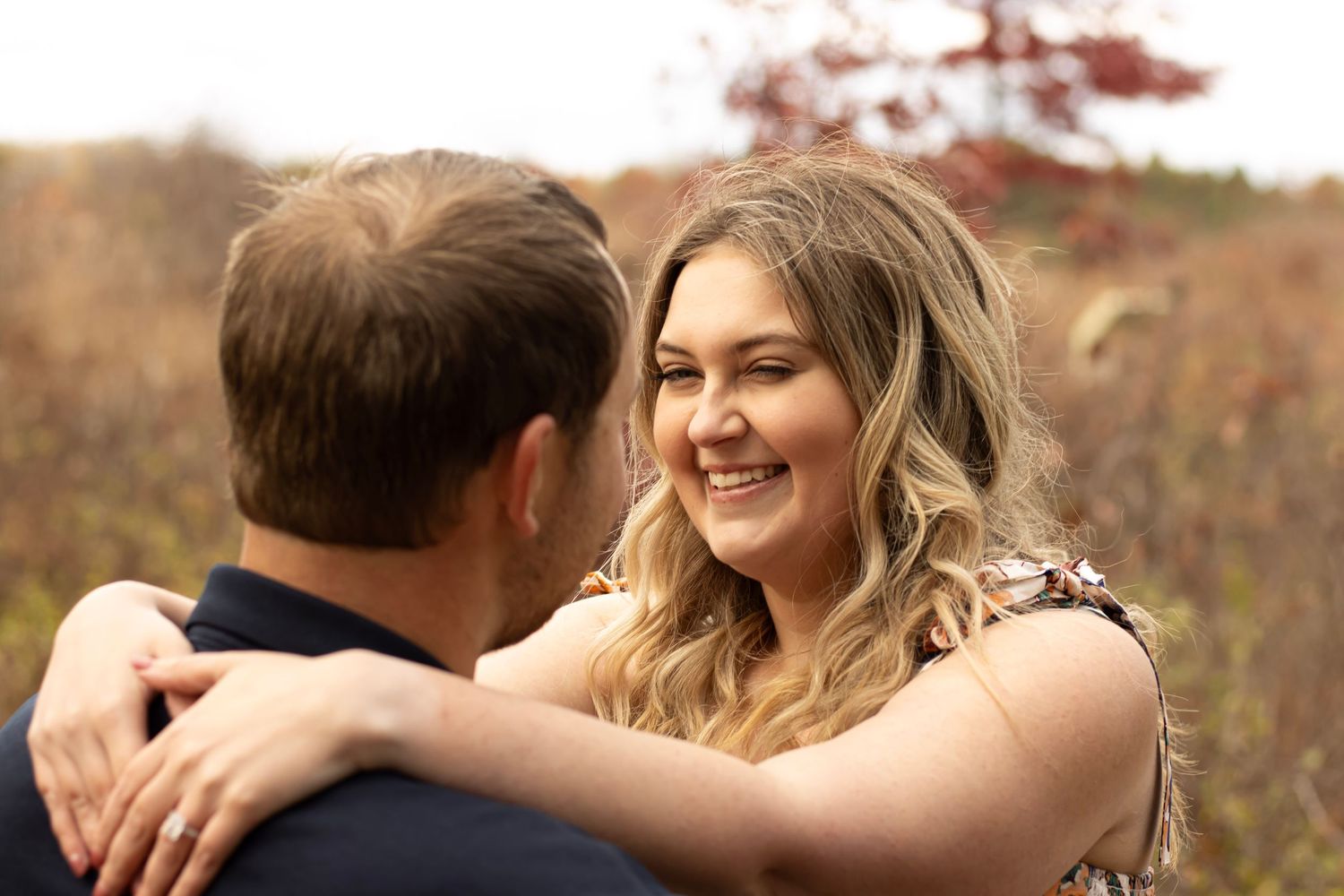 Romantic autumn engagement photoshoot showing couple embracing in warm natural lighting.