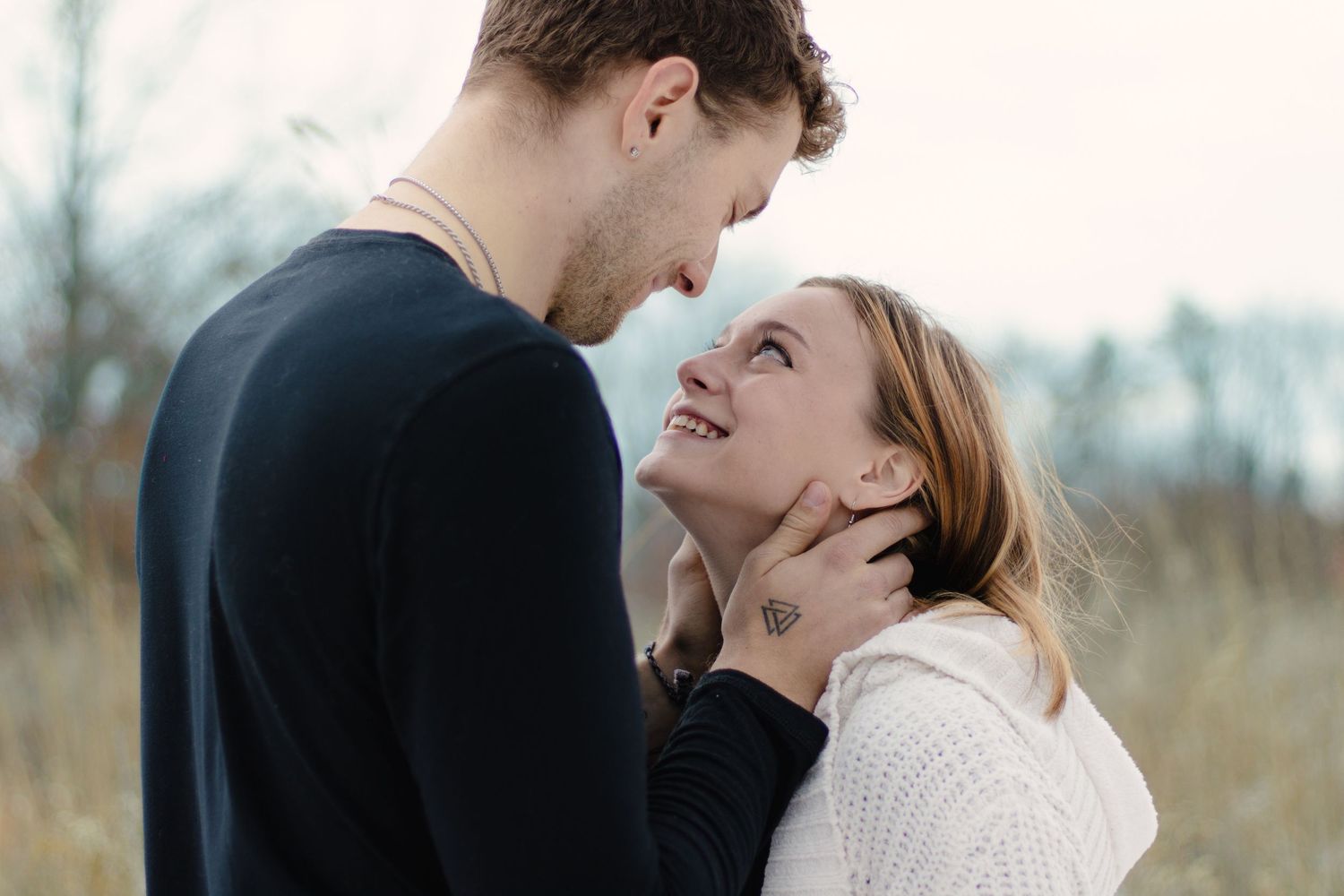 Intimate winter engagement photo of couple sharing tender moment in snow.