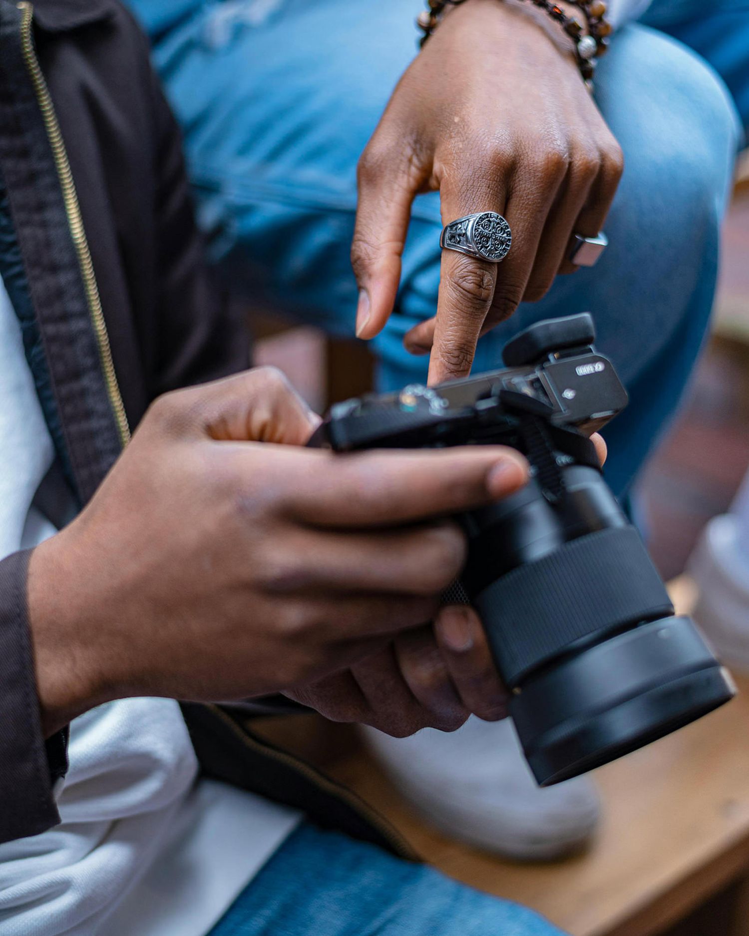 Close-up sequence of hands handling a camera during a photography mentoring session.