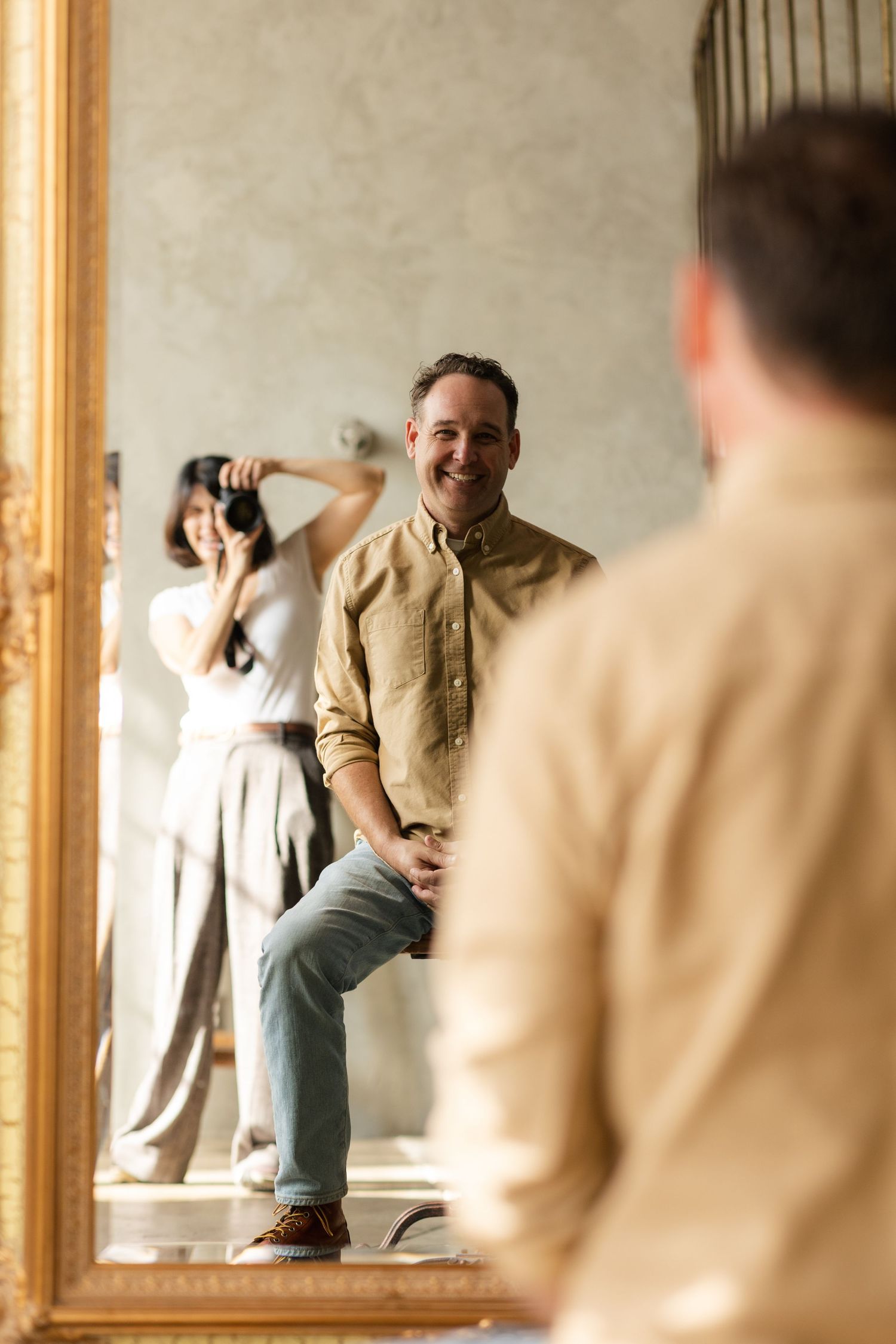 Person in casual attire posing playfully in front of vintage gold-framed mirror.