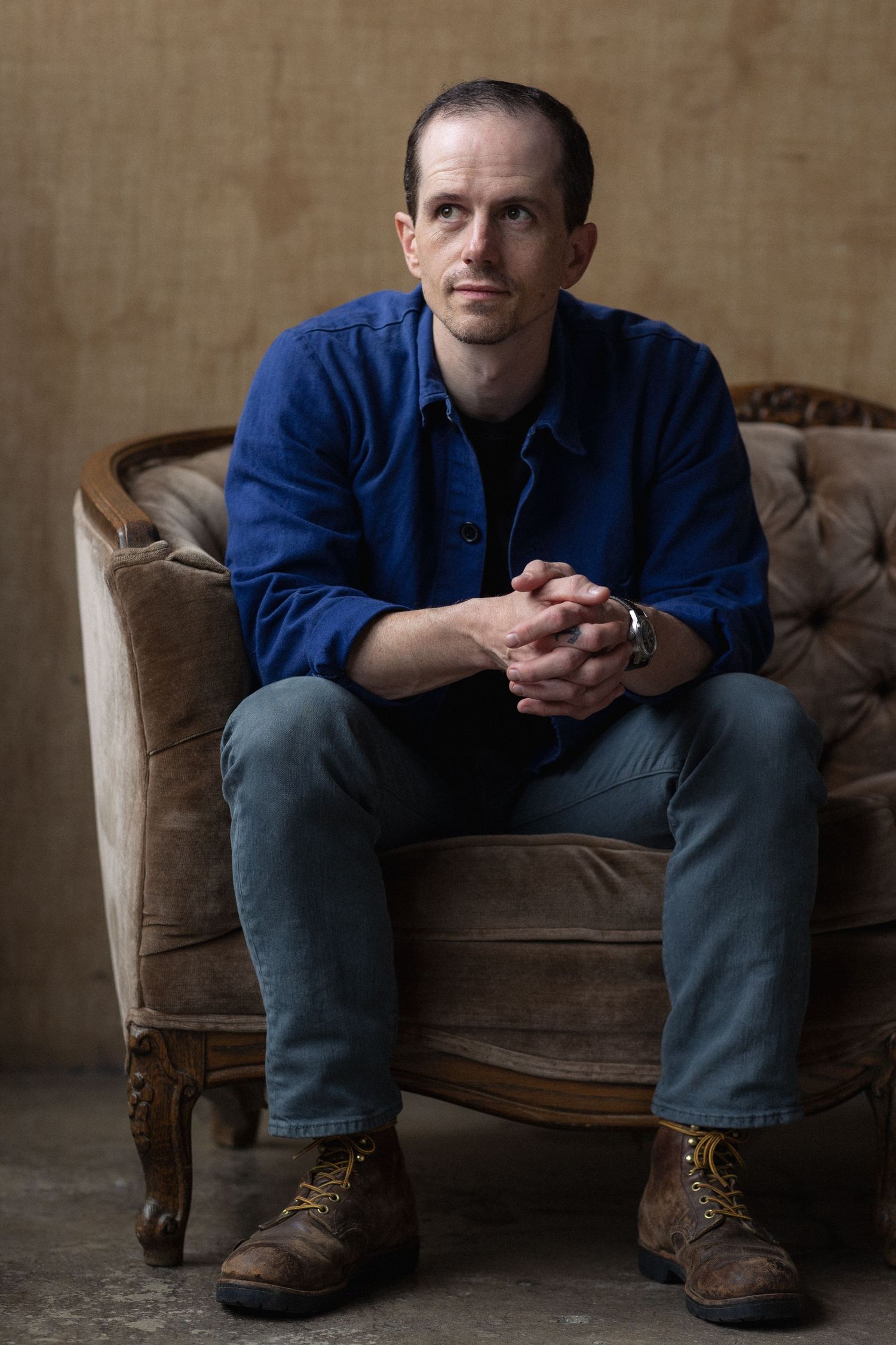 Person in blue shirt and jeans sitting on a vintage brown leather chair.