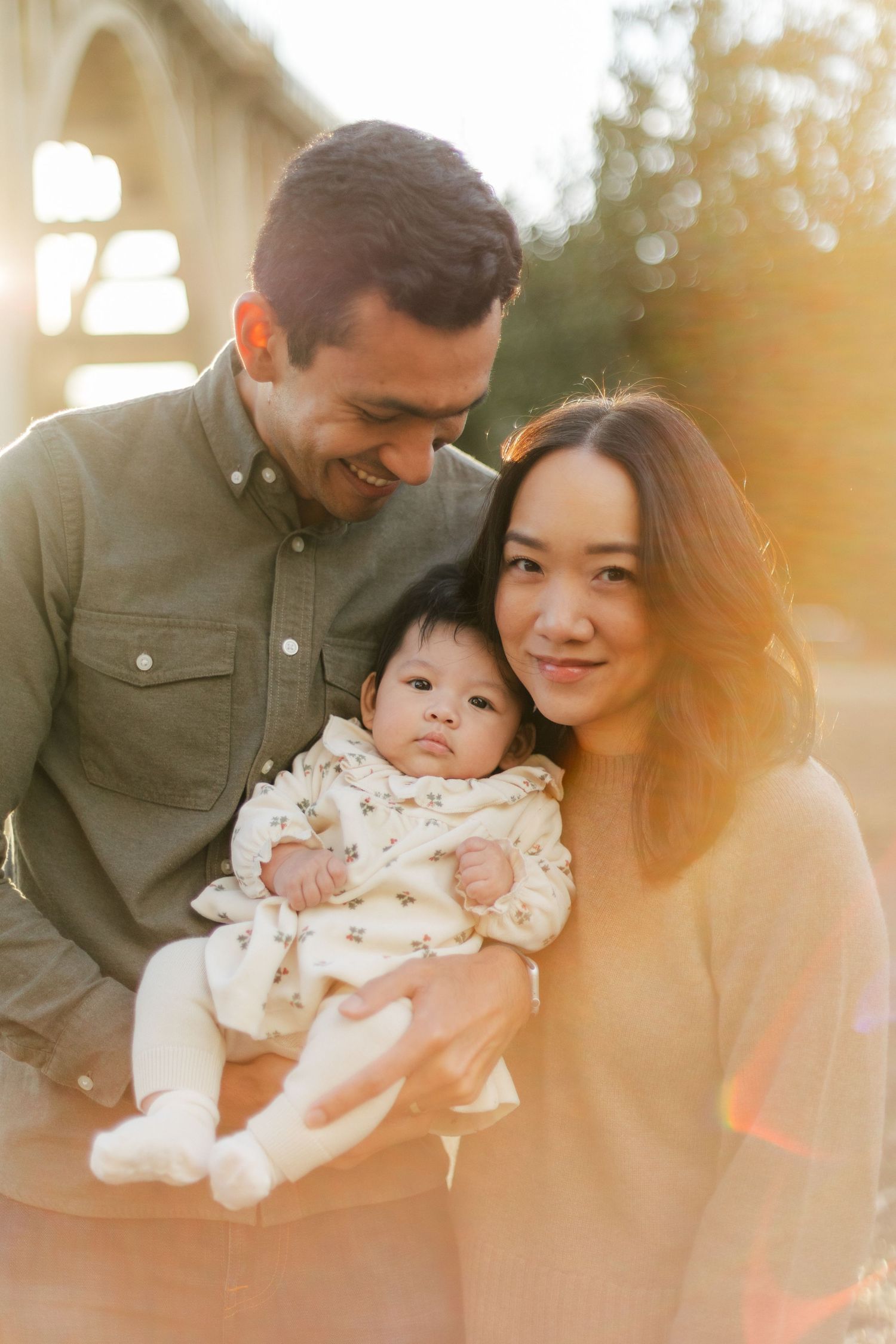 A family shares tender moments together in warm sunlit photos with their baby.