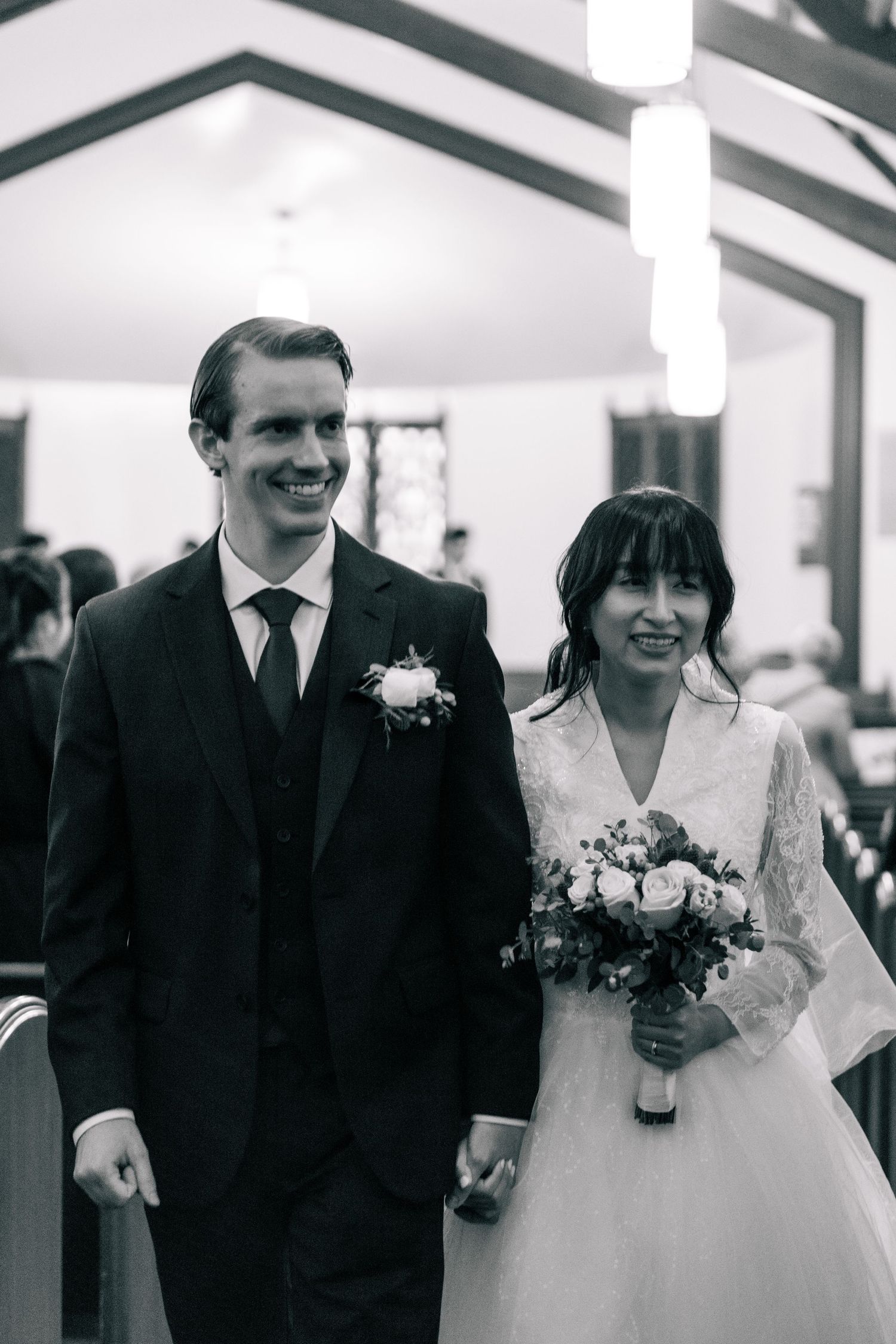 Black and white wedding portrait of a couple walking together in formal attire.