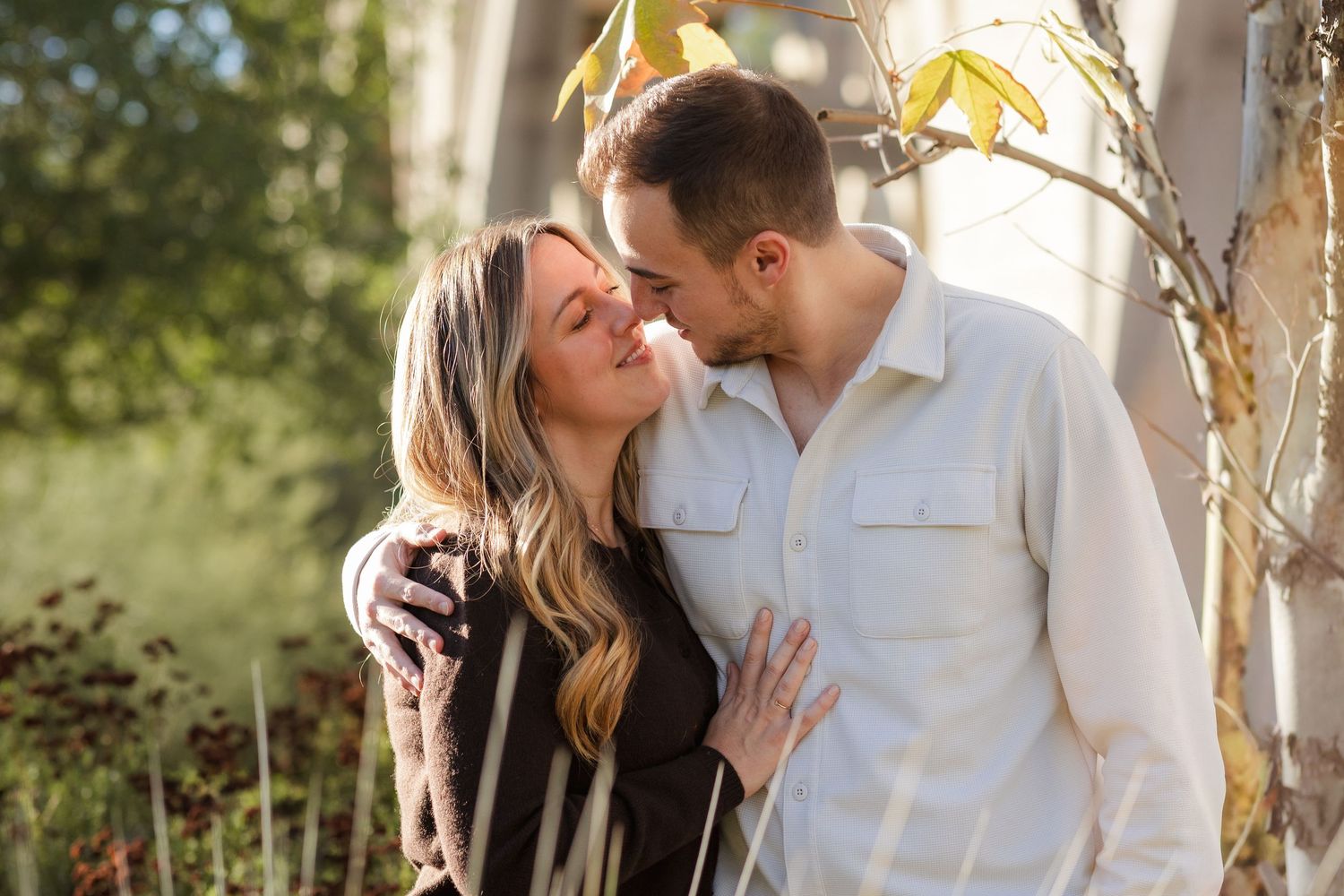 A couple shares an intimate moment outdoors during a golden hour photoshoot.