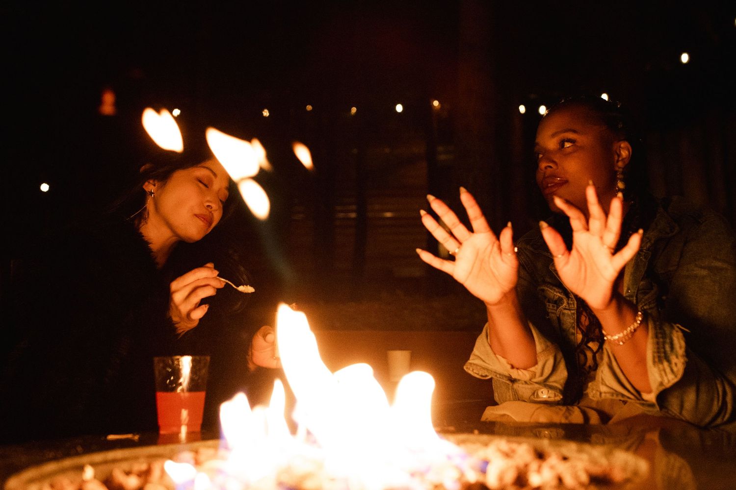 Nighttime outdoor celebration with fire pits and string lights creating warm ambiance.