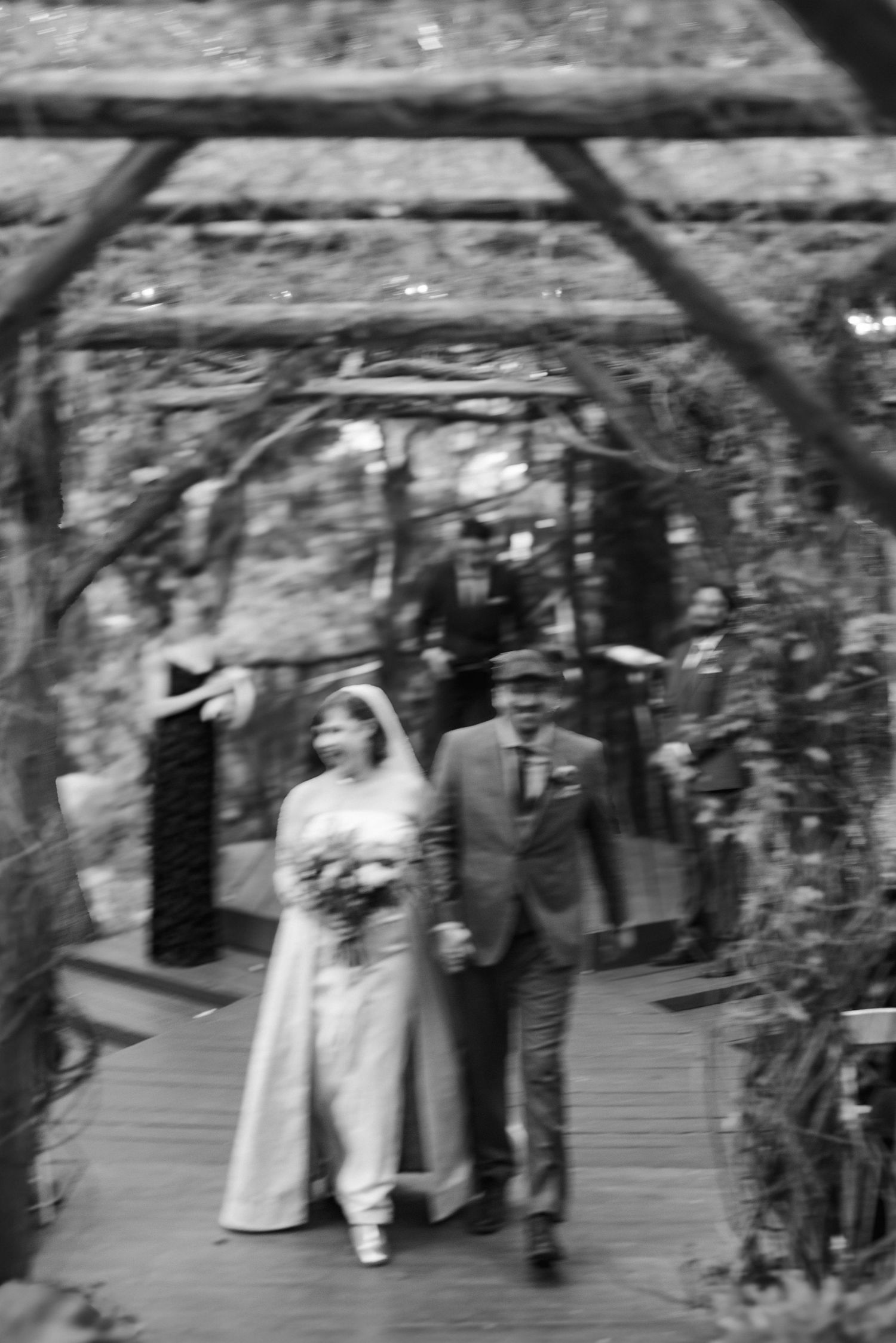 Blurred black and white wedding ceremony photos under natural outdoor archway.
