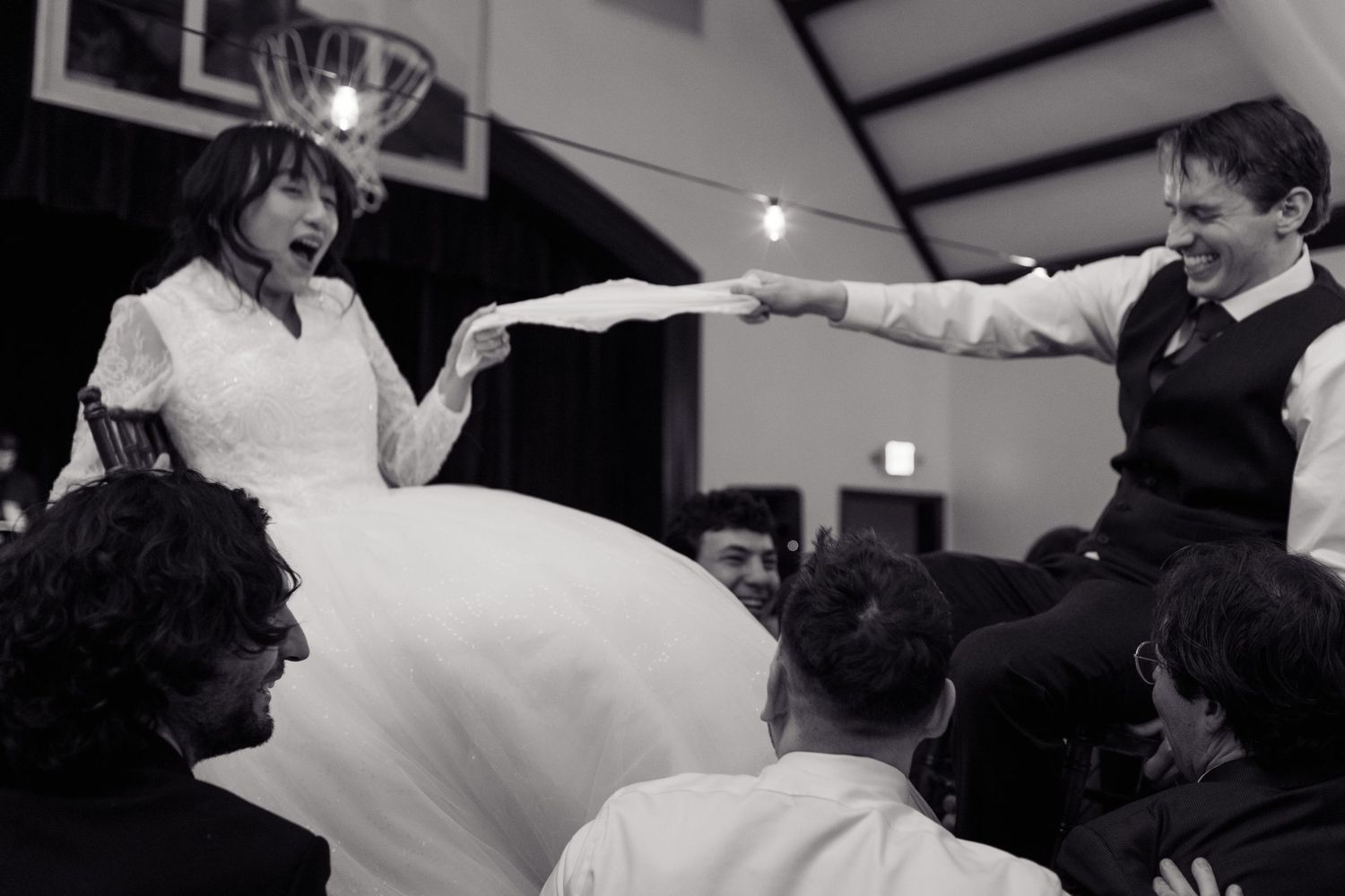 Celebratory dance moves captured in black and white at an indoor reception.