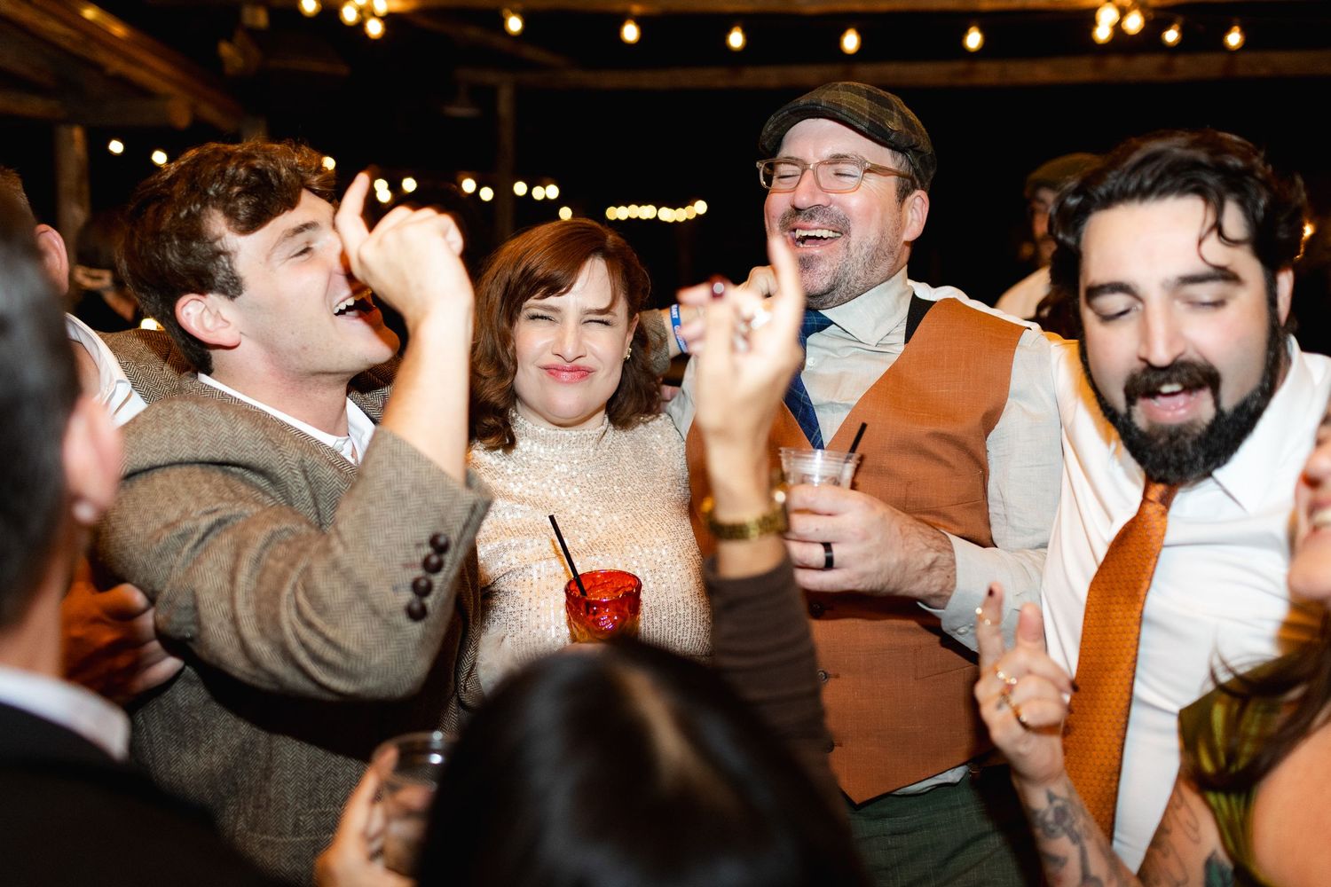 Wedding reception guests celebrating and dancing under warm indoor lighting.
