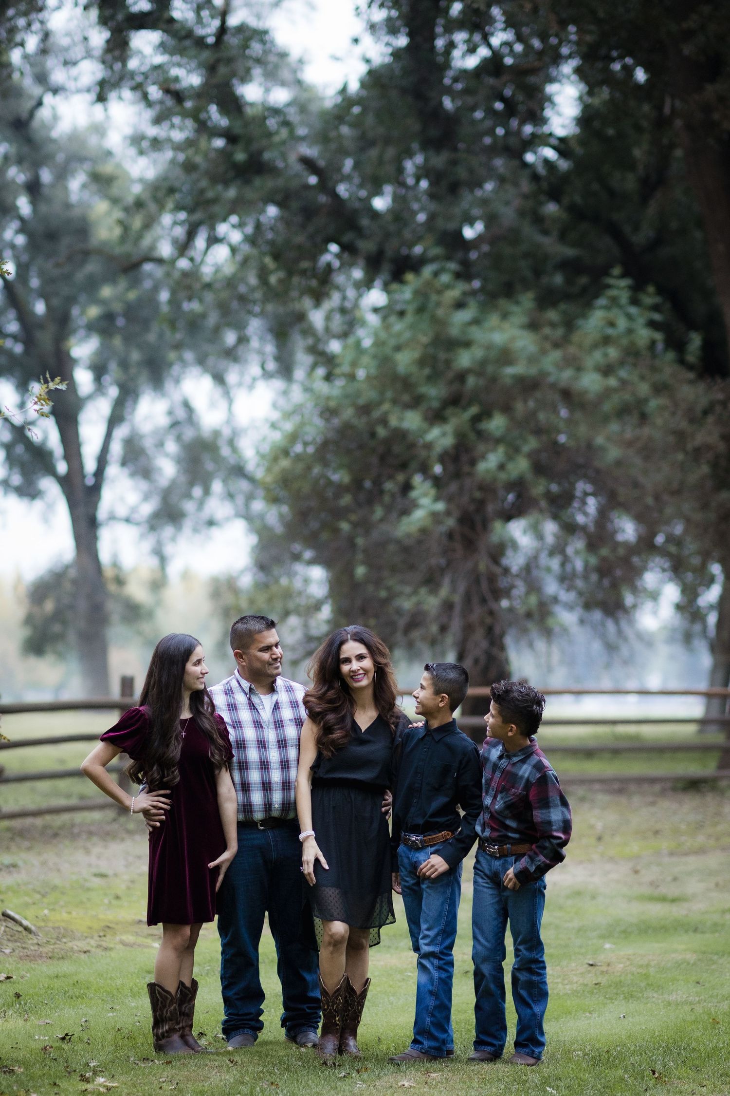 Group photo session in a park setting with trees and natural lighting creating a dreamy atmosphere.